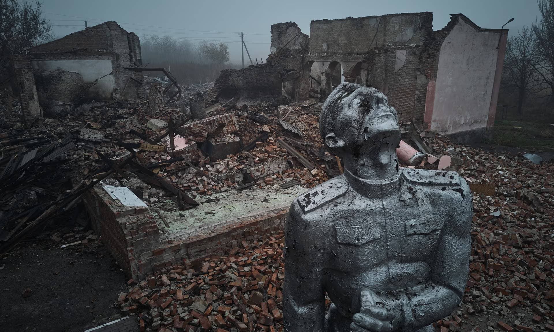 A statue of a Soviet soldier against the background of a house of culture destroyed by rocket fire in Avdiivka