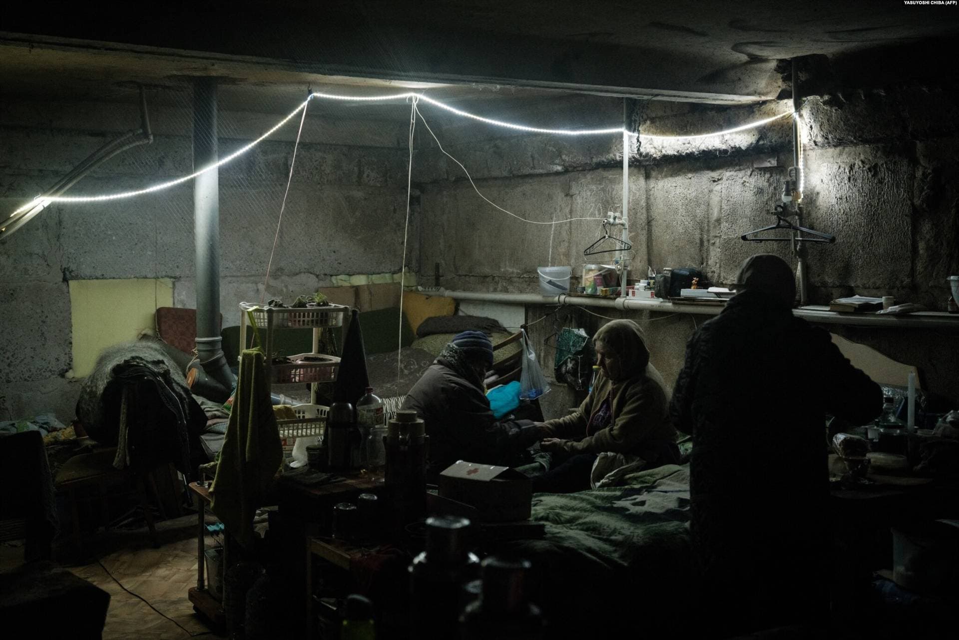 Halyna and Tetyana take turns massaging each other's hands to keep them warm