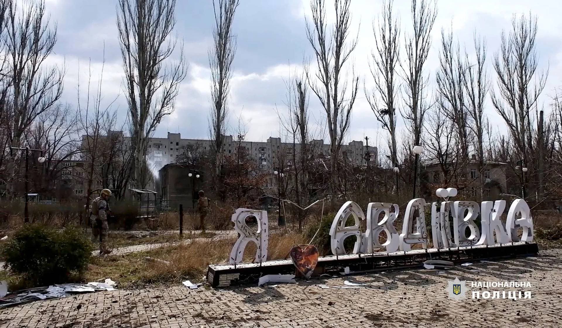 Police officers walk near a sign in Avdiivka