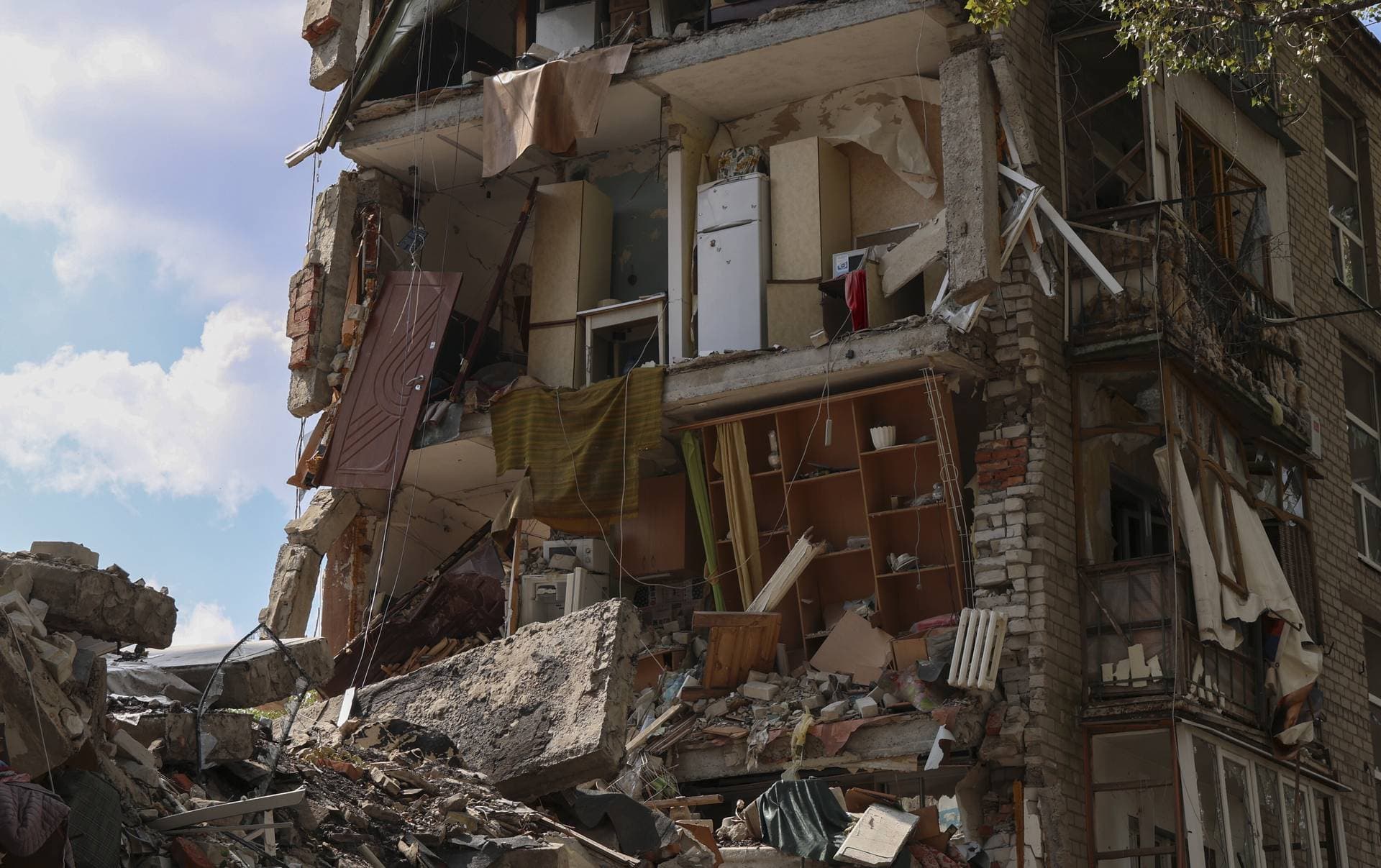 A damaged residential building stands on a shelled street in Avdiivka settlement