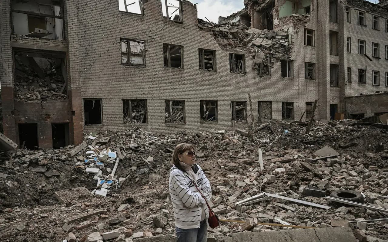 A woman stands in front of a destroyed administration building in the city of Bakhmut