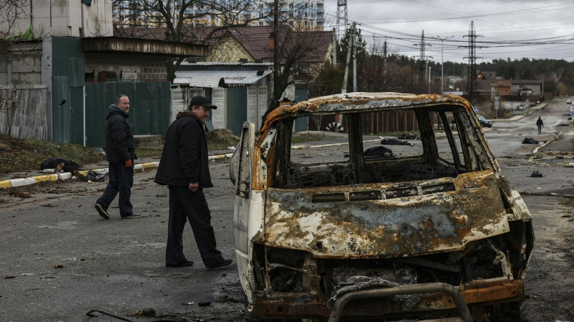 People walk on a street with several dead bodies on the ground a street in Bucha, northwest of Kyiv.