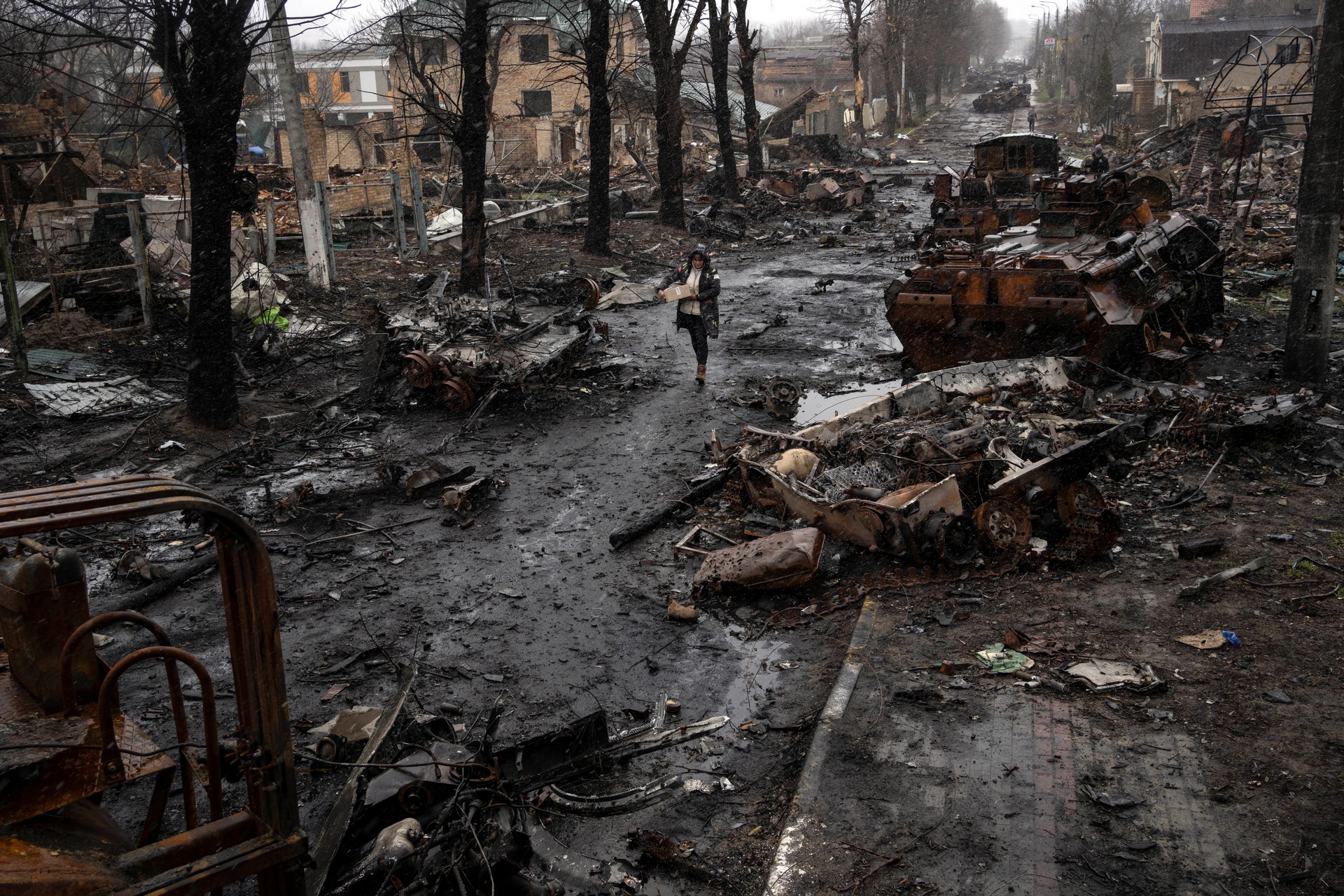 A woman walks amid destroyed Russian tanks in Bucha