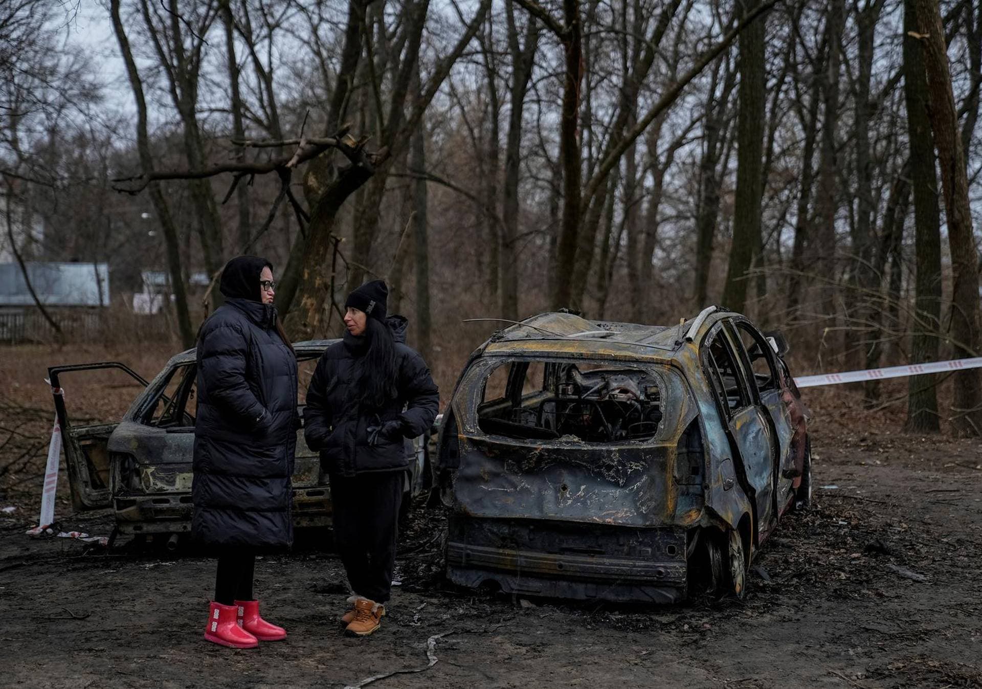 Residents stand near burned cars at the site of a Russian drone strike in Chernihiv