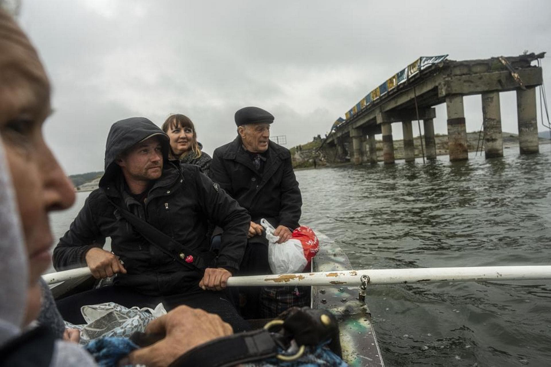Anton Krasyvyi rows passengers across the Siverskyi-Donets river in front of a destroyed bridge, so they can visit relatives in Staryi-Saltiv