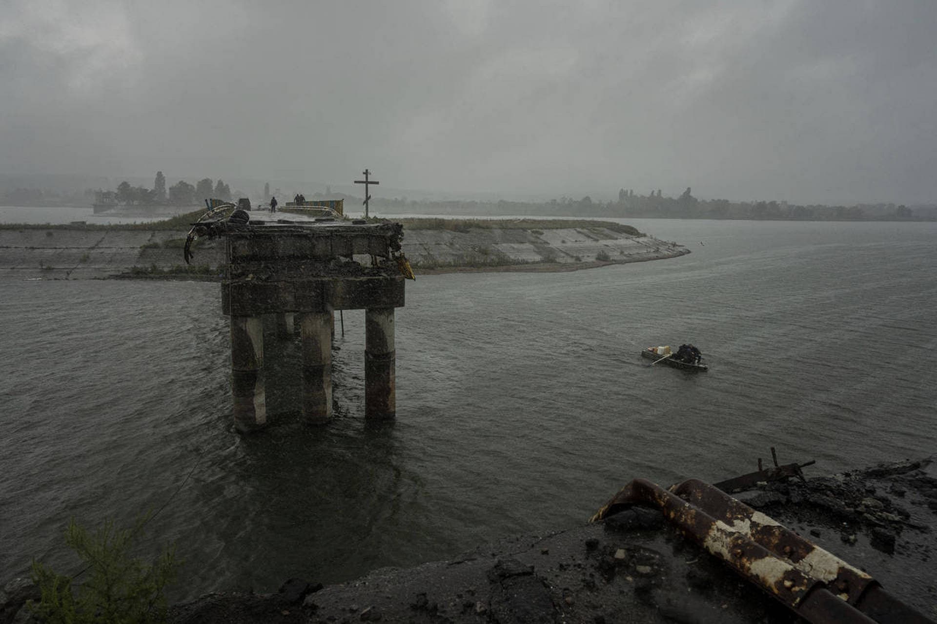 People transport fuel on a boat in front of a destroyed bridge across the Siverskyi-Donets river in Staryi-Saltiv
