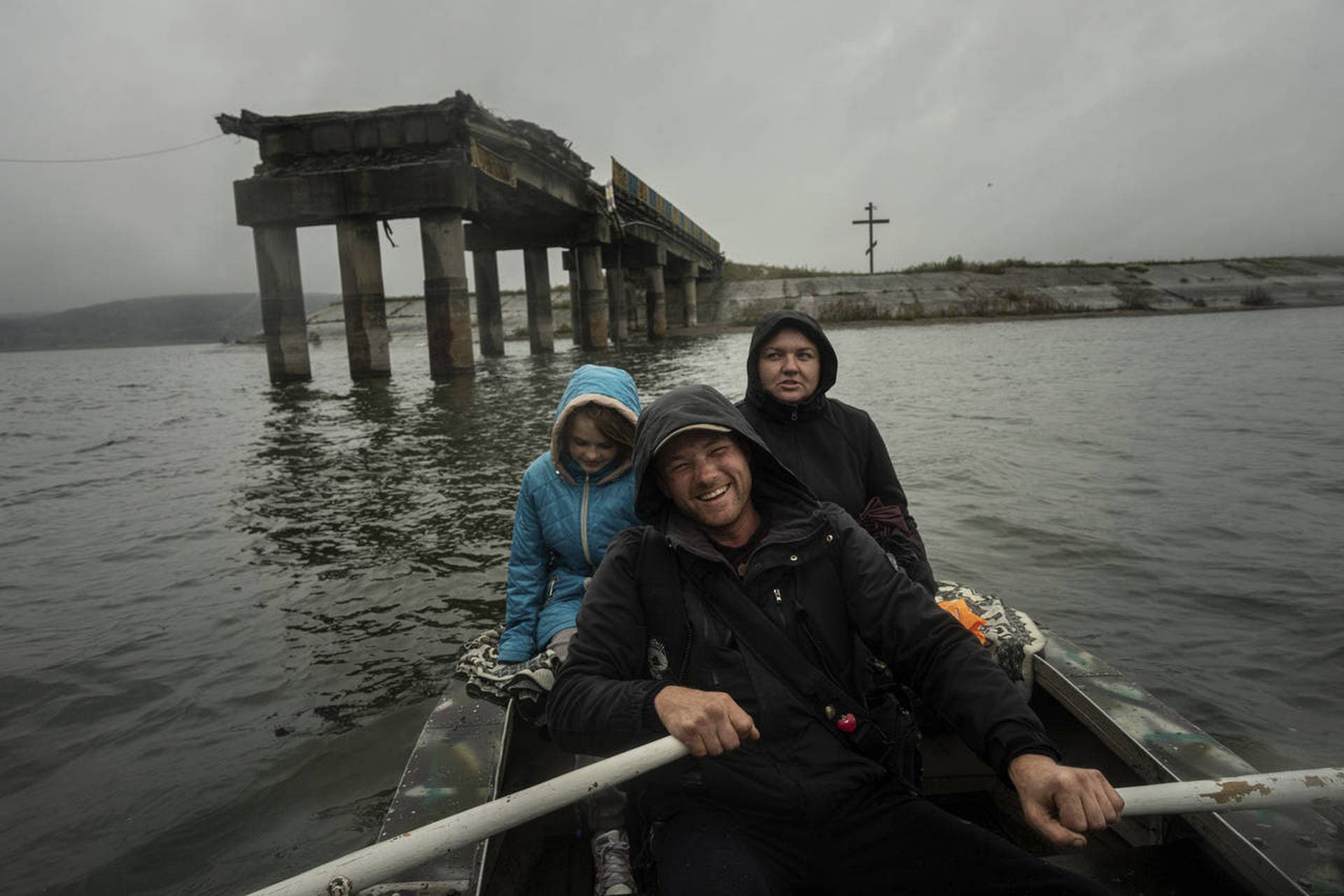 Anton Krasyvyi rows passengers Maryna and her daughter Arina across the Siverskyi-Donets river in front of a destroyed bridge so they can visit relatives in Staryi-Saltiv
