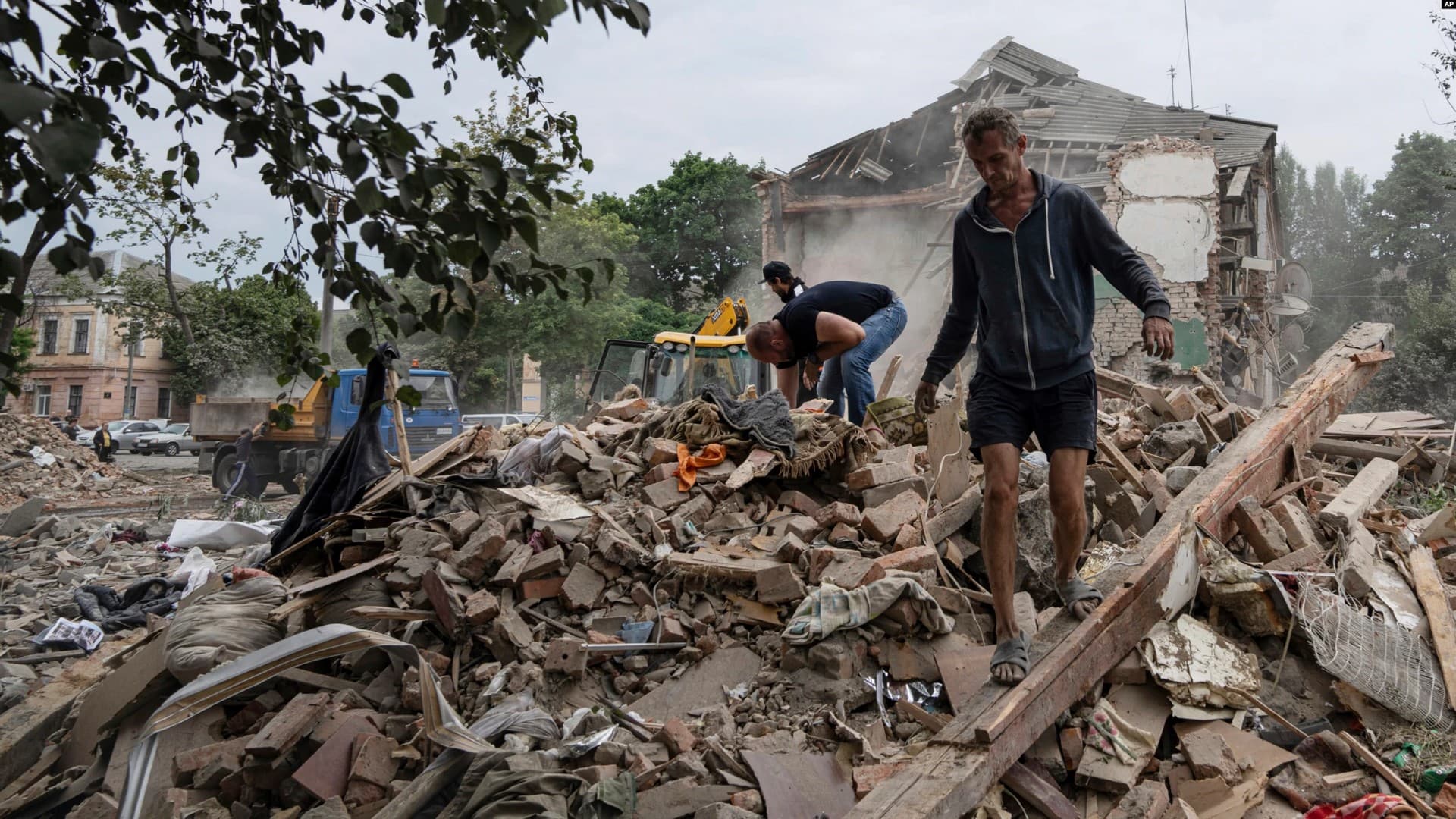 Local residents search for the documents of their injured friend in the debris of a destroyed apartment house after Russian shelling in a residential area in Chuhuiv