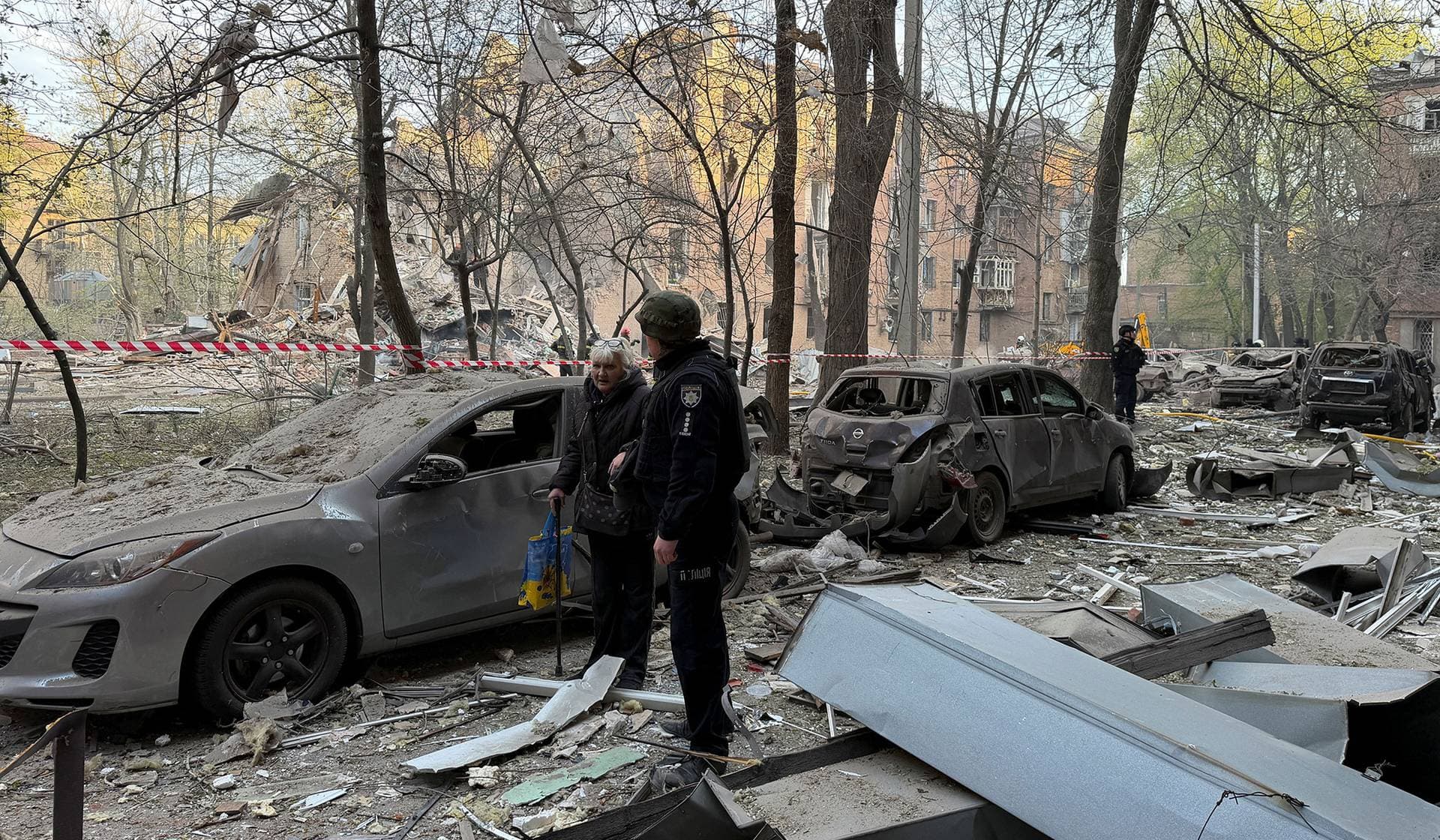 A police officer evacuates a resident at a site of an apartment building hit by a Russian drone and missile strike in Dnipro