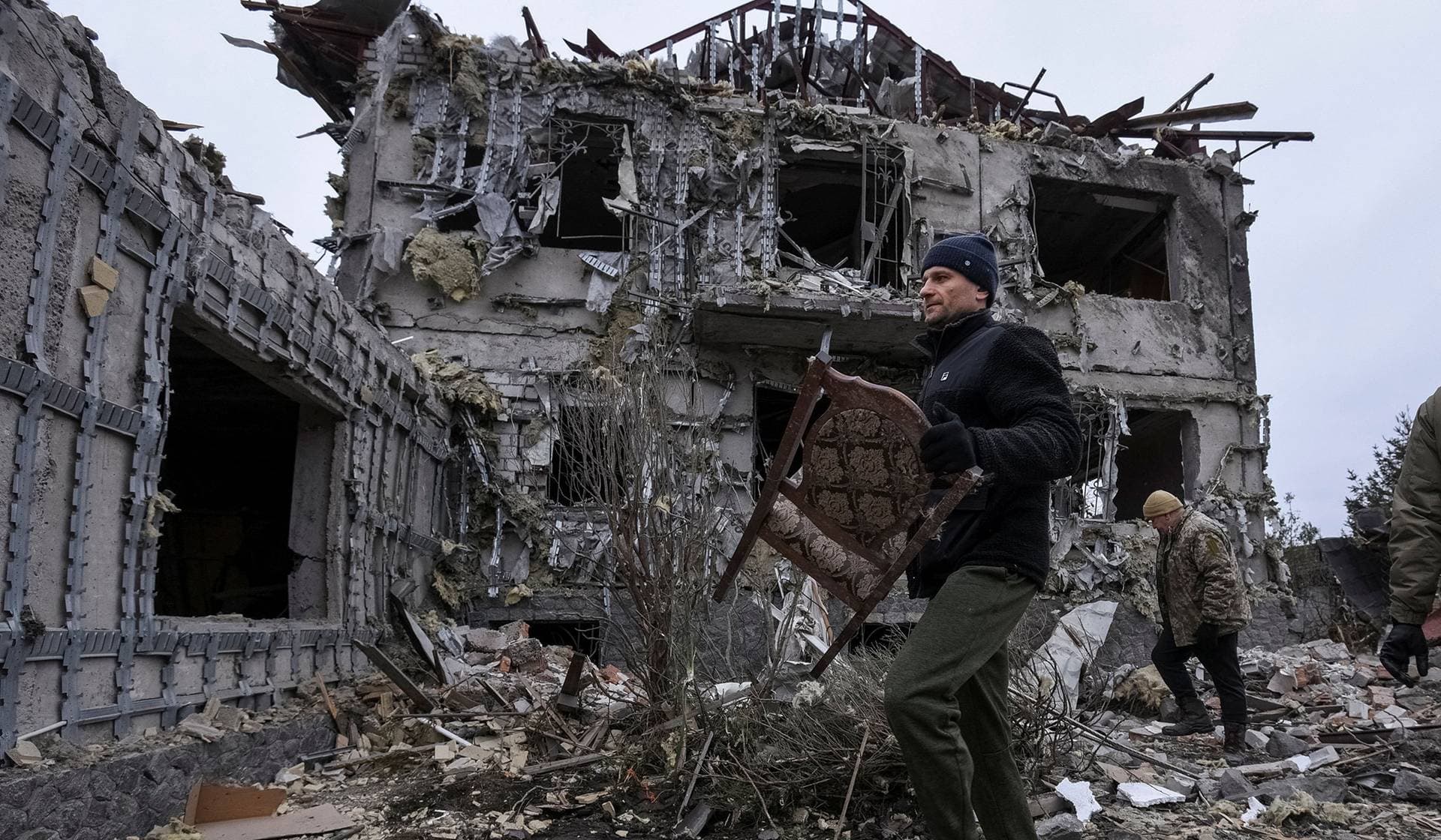 A resident carries a chair collected from a building hit during the Russian missile and drone strike in Slobozhanske