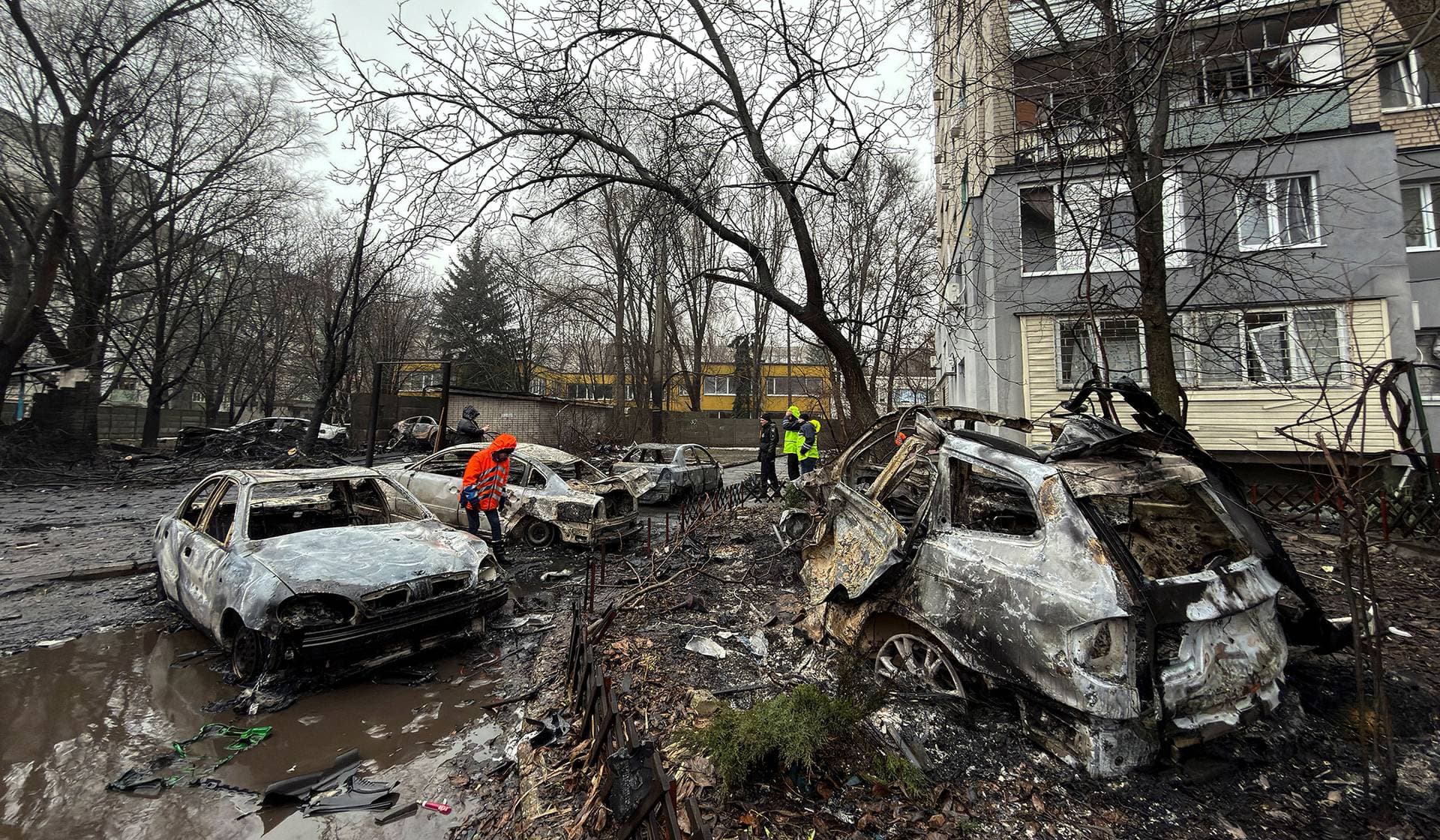 Police officers and residents inspect cars destroyed by a late evening Russian drone strike in Dnipro