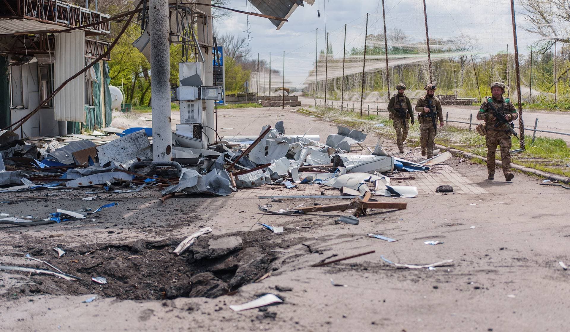 Servicemen walk along a street near an anti-drone net in the frontline town of Druzhkivka
