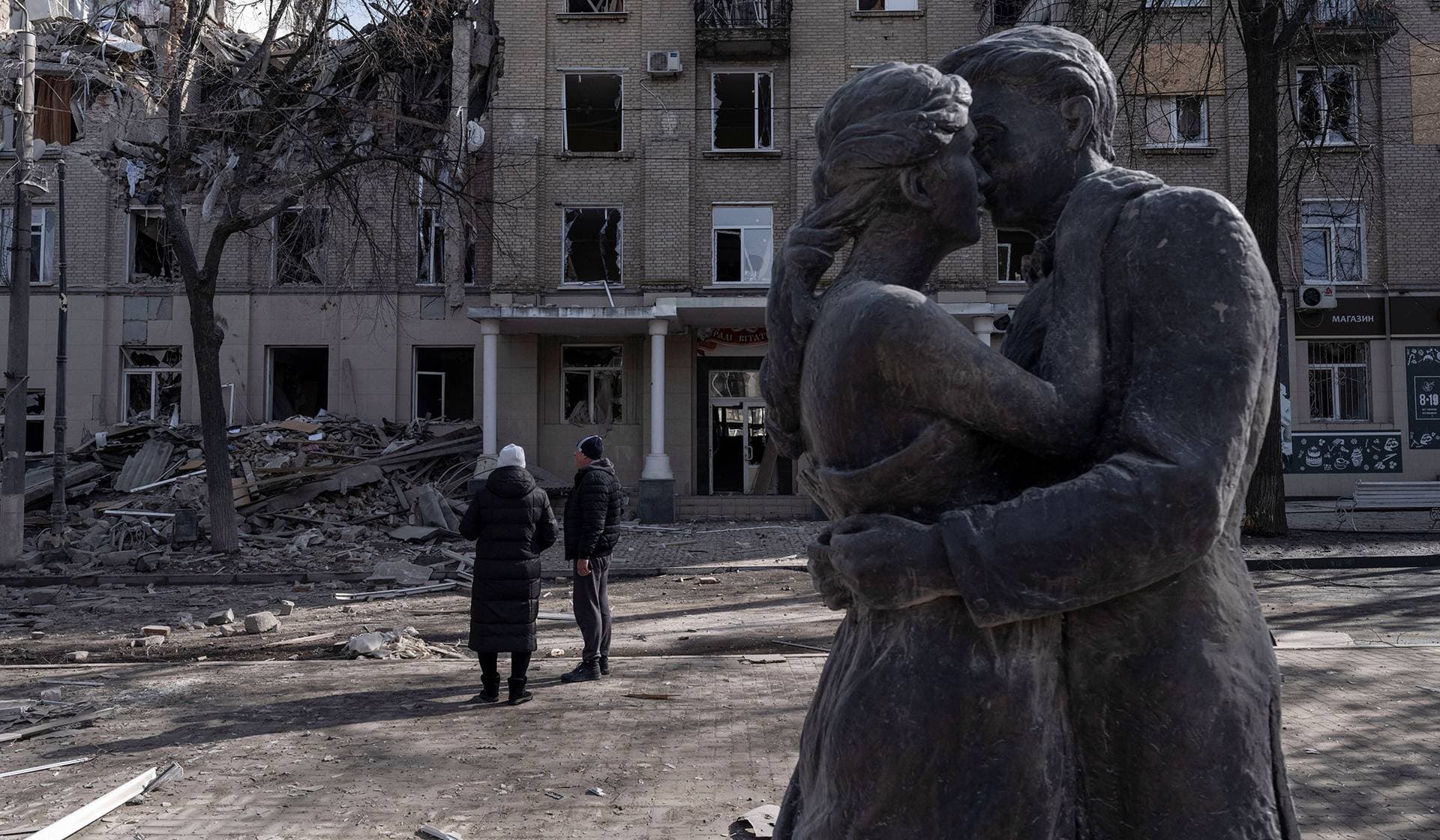 Residents stand at a site of a Russian air strike, in the frontline town of Druzhkivka