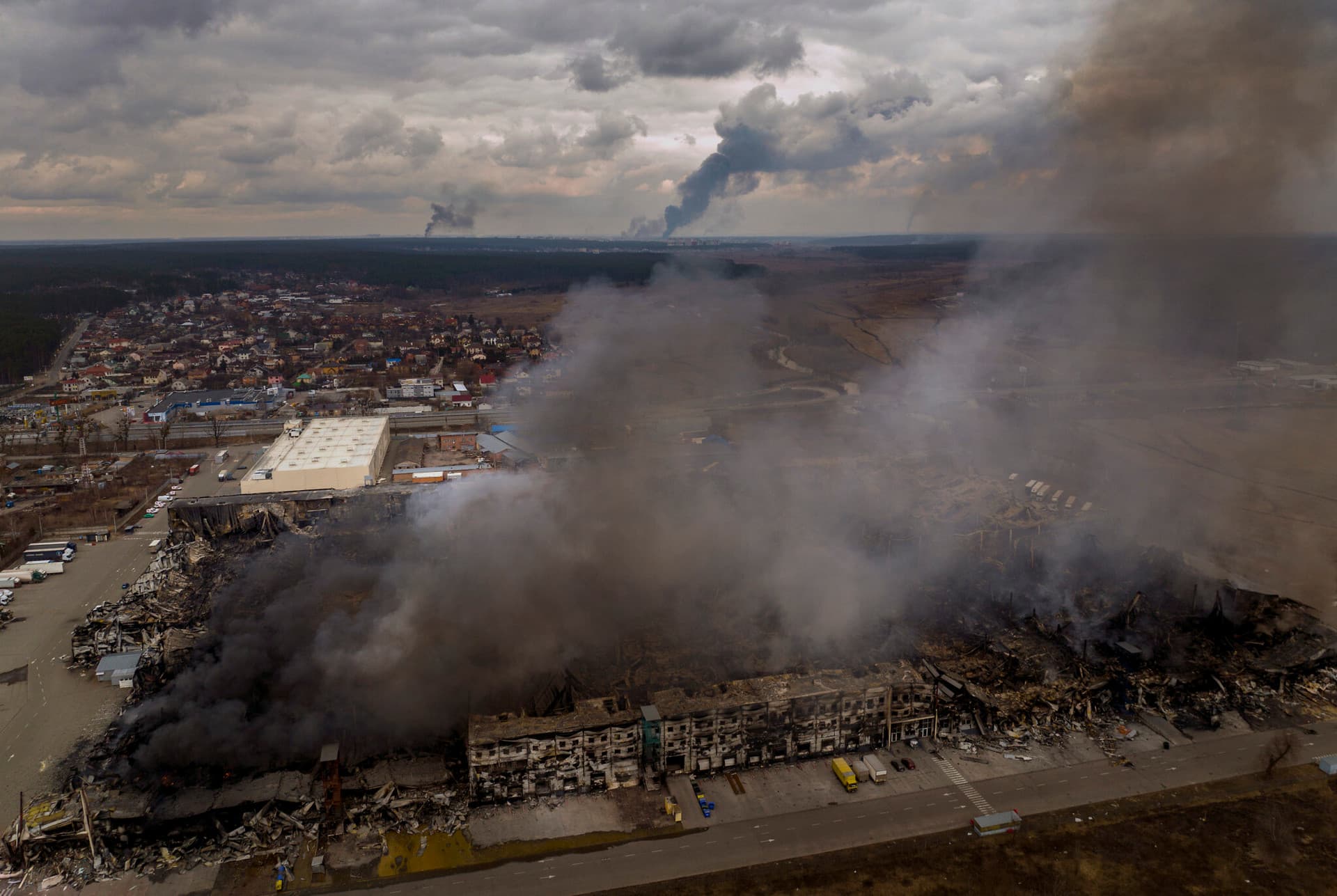 A factory and a store burn after having been bombarded in Irpin