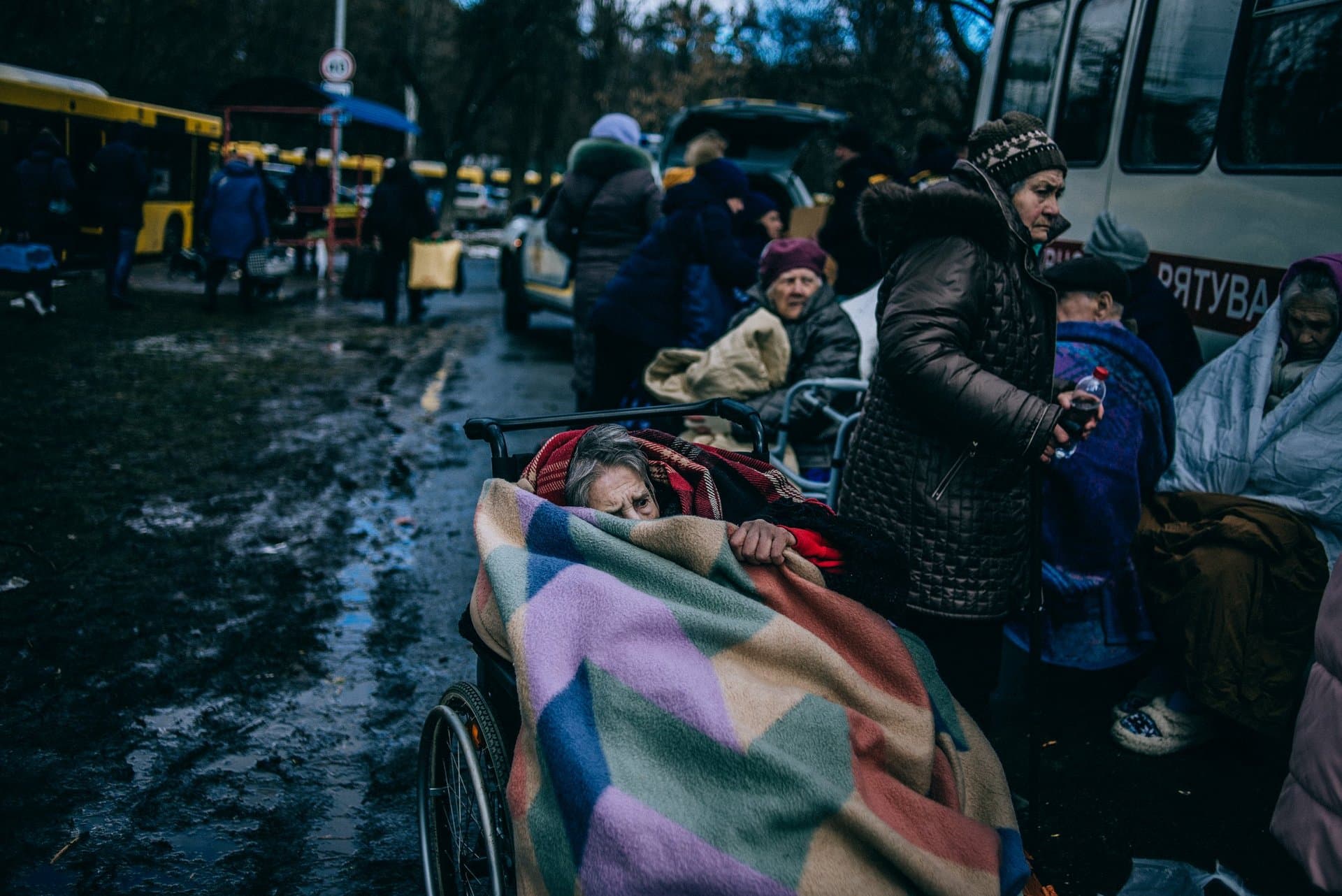 An elderly woman hides under a blanket after she being evacuated from Irpin