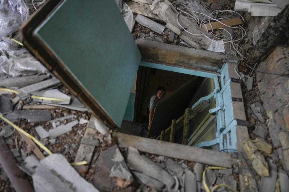 Liudmyla Voronina opens a skylight window on the roof of her house roof as she stands inside her home that was damaged by attacks in Irpin