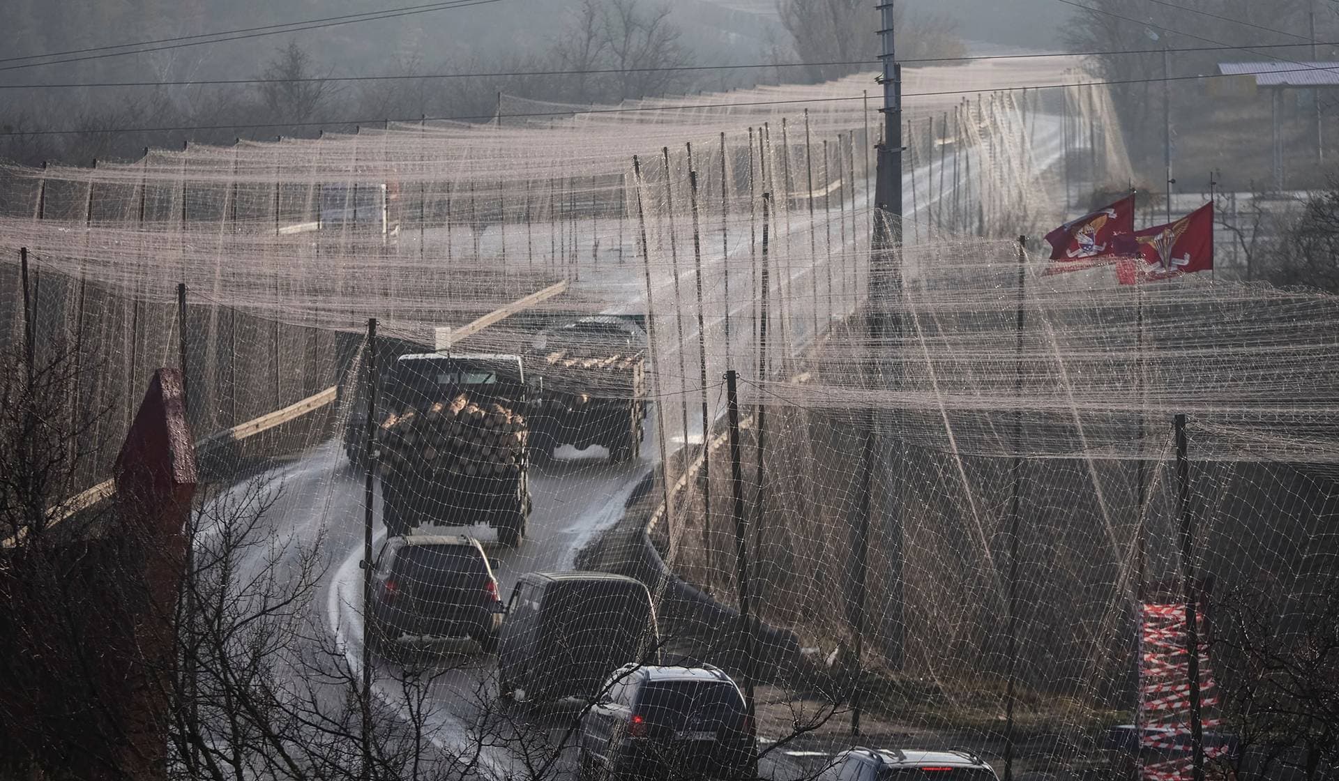 Cars drive along a road covered with an anti-drone net in Izum