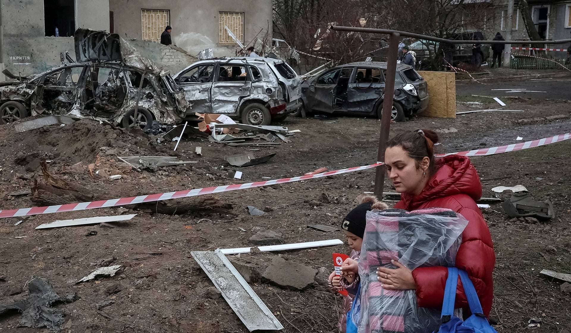 Residents carry humanitarian aid at the site of apartment buildings damaged during Russian missile strikes in the town of Balakliia