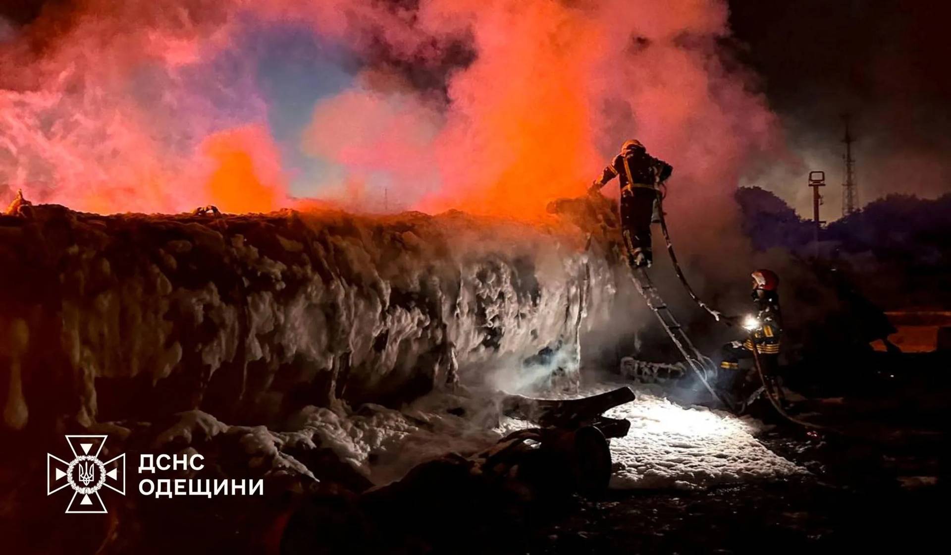 Members of emergency services work as smoke rises in the aftermath of a Russian drone strike in a location given as Izmail