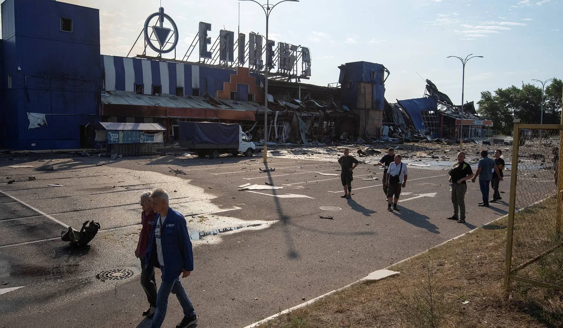Employees walk at the site of a household item shopping mall which was hit by a Russian missile strike in Kamianske