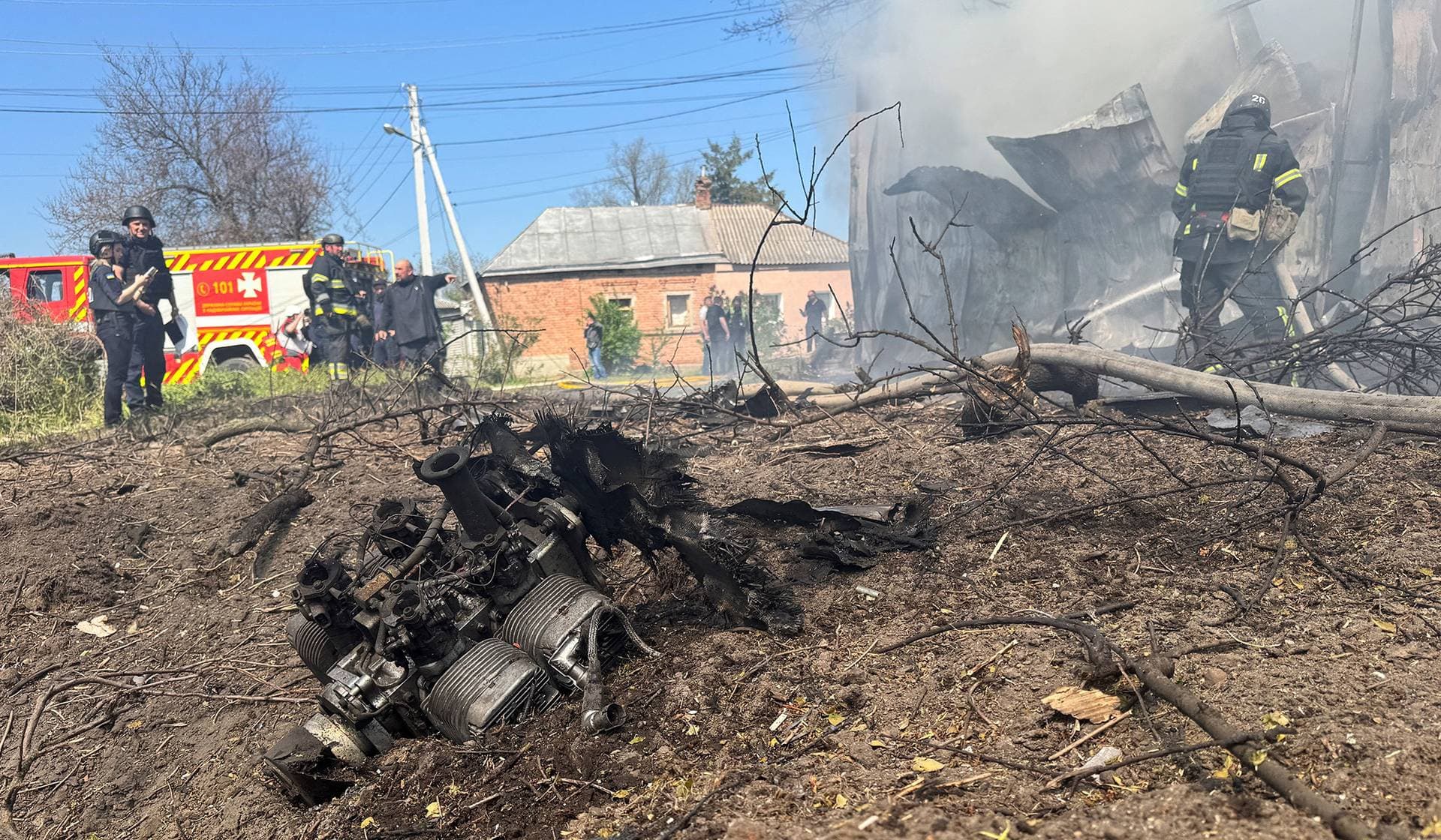 An engine of a Russian drone lays on the ground as rescuers work at the site of a Russian drone strike in Kharkiv