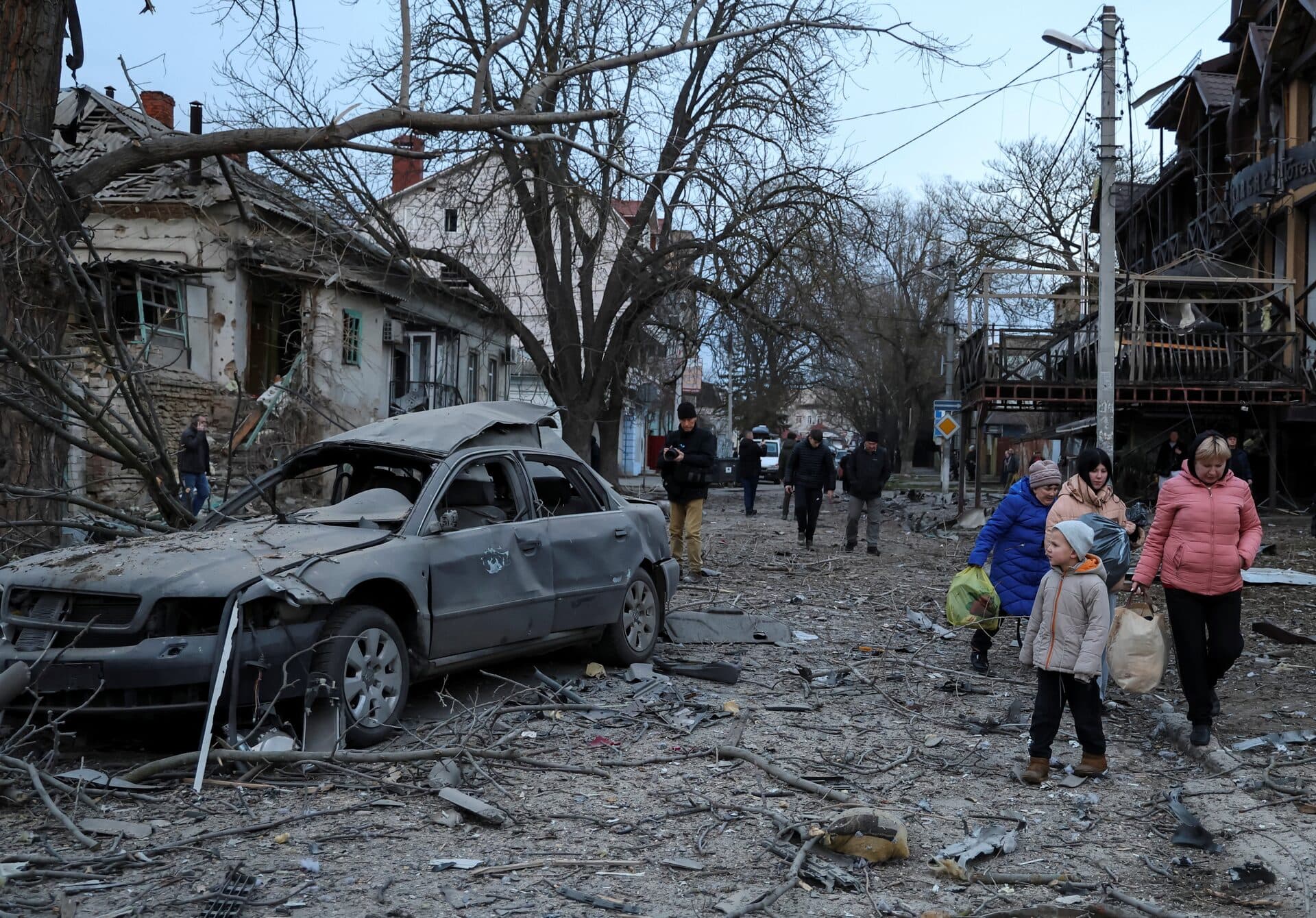 Residents leave from a site of apartment buildings hit by a Russian air strike in Kherson