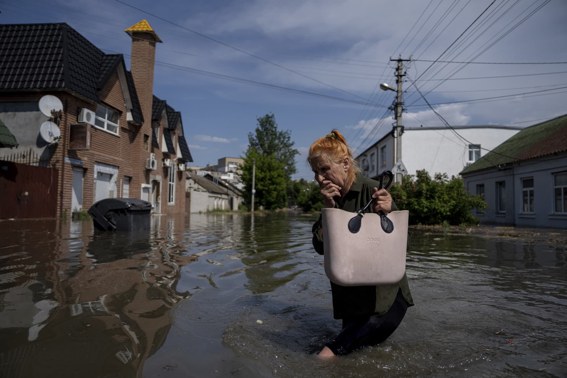 A local resident makes her way through a flooded road after the walls of the Kakhovka dam collapsed overnight, in Kherson