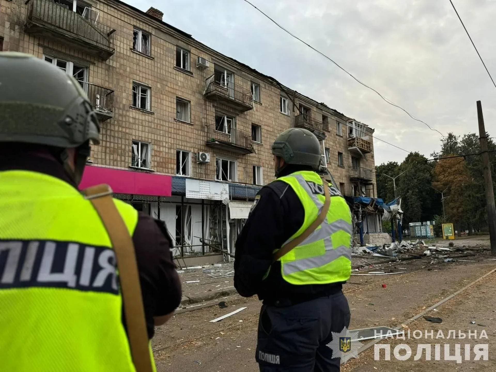 A police officer takes a picture of a residential building damaged during a Russian drone strike in Konotop