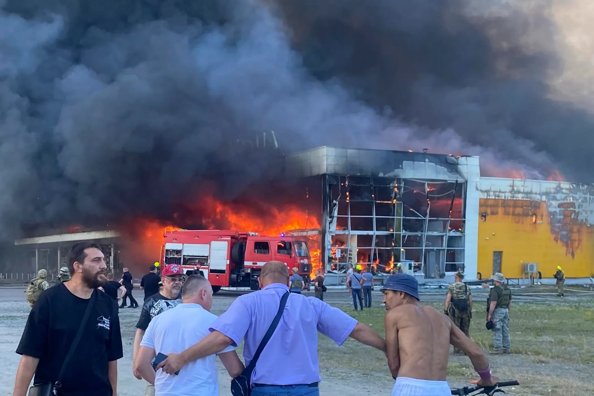 People watch as smoke bellows after a Russian missile strike hit a crowded shopping mall, in Kremenchuk