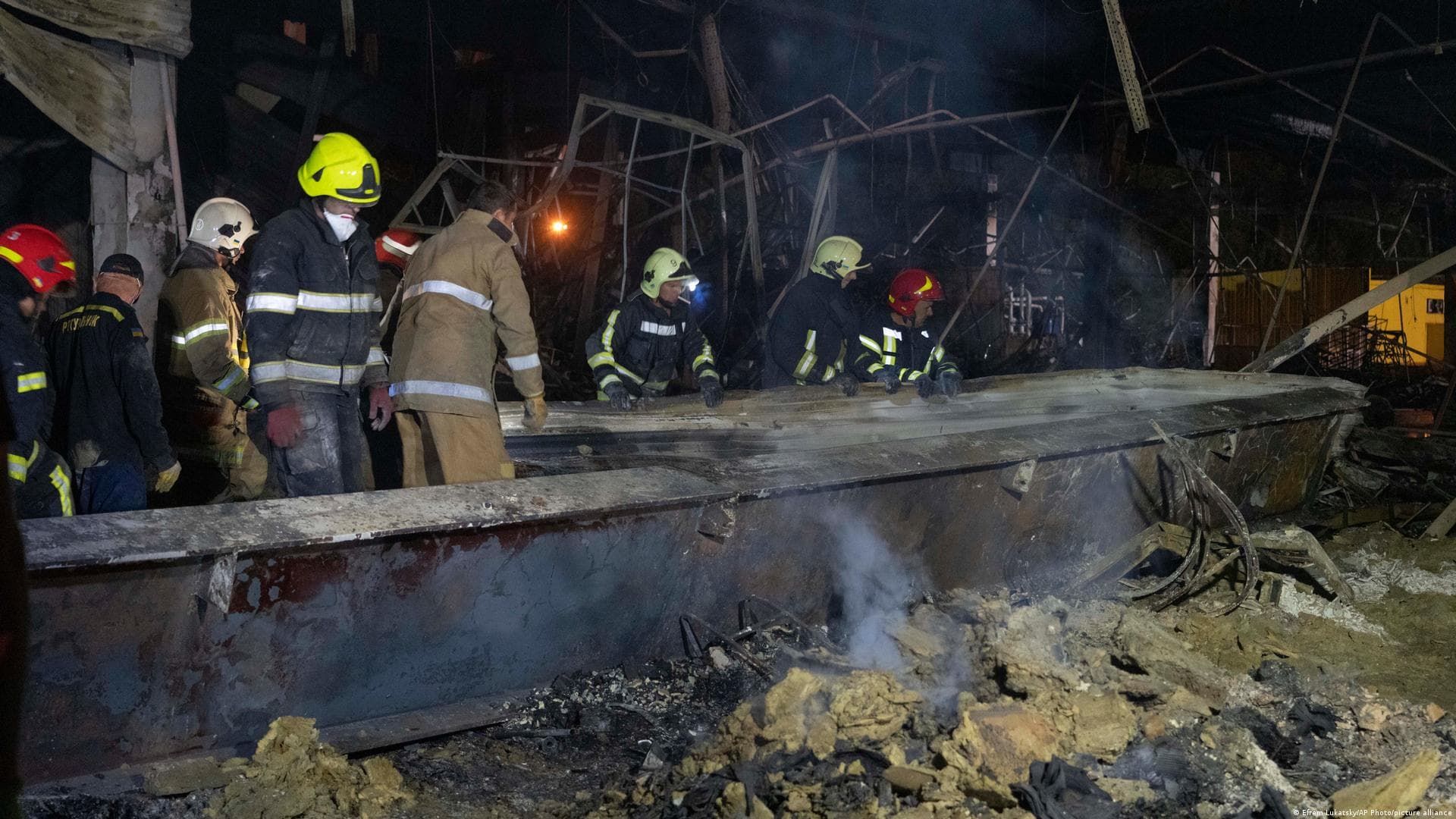 Ukrainian State Emergency Service firefighters to take away debris at a shopping center burned after a rocket attack in Kremenchuk