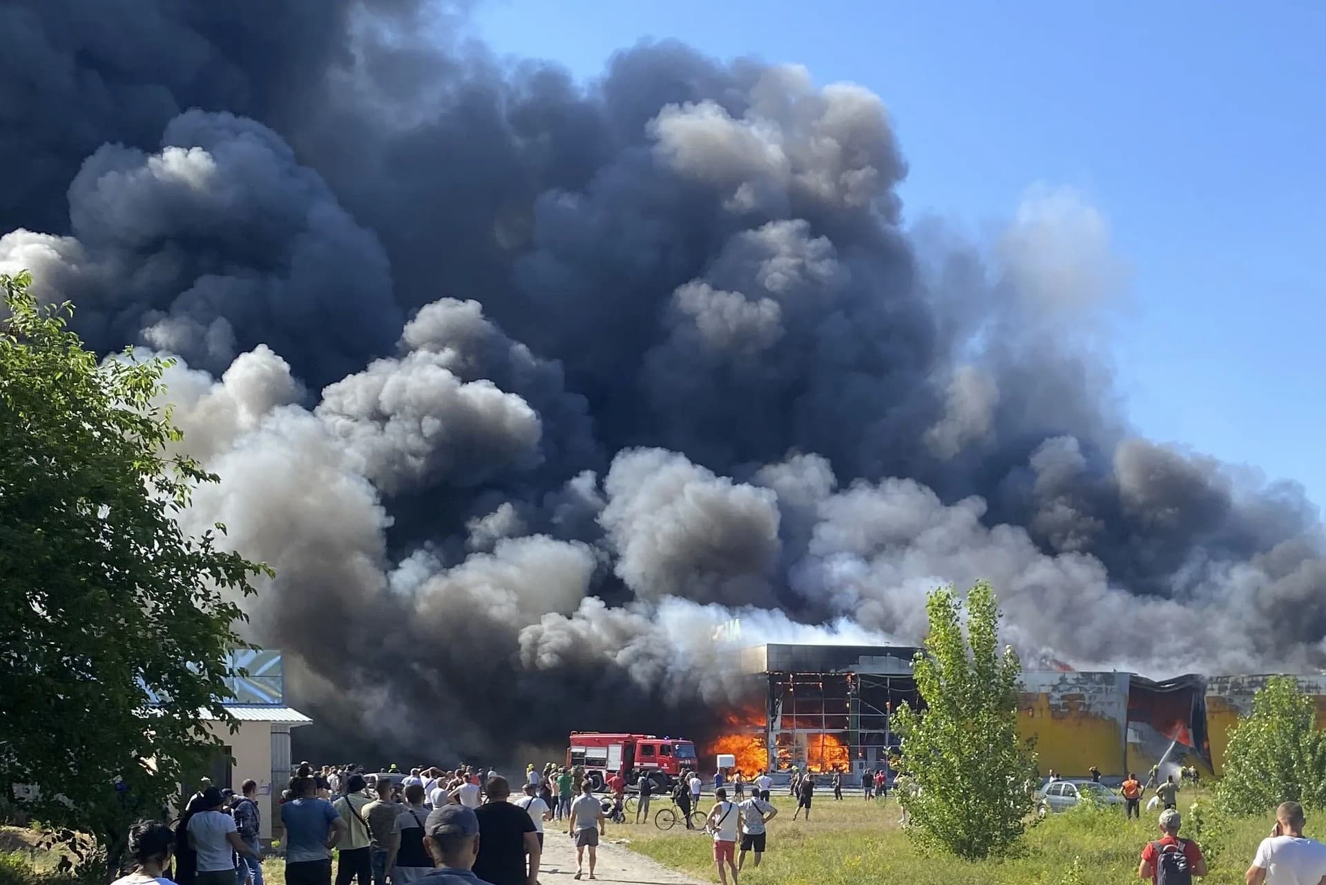 People watch as smoke bellows after a Russian missile strike hit a crowded shopping mall, in Kremenchuk