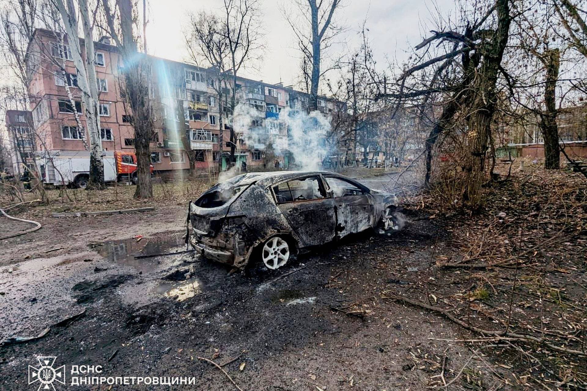 A burning car in front of an apartment building damaged by a Russian missile strike in Kryvyi Rih