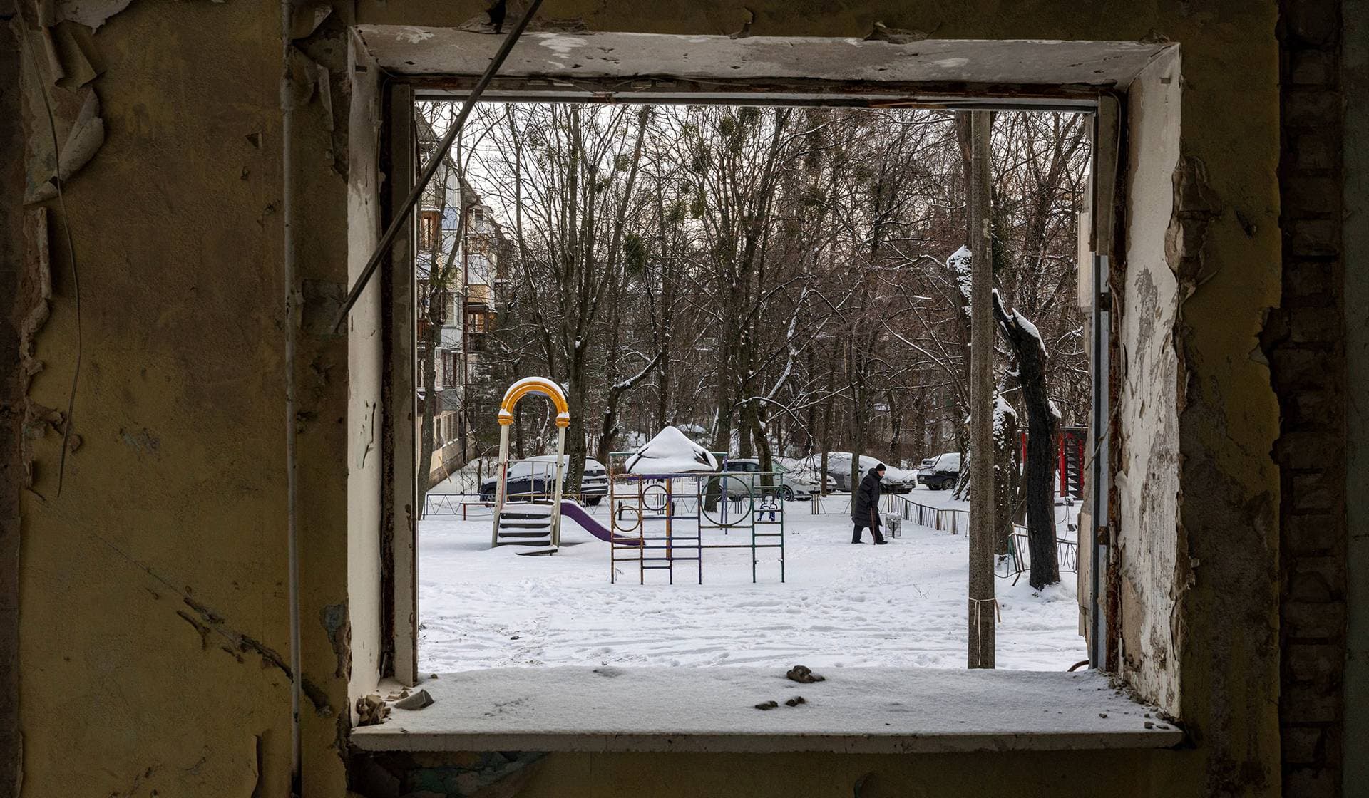 A man walks on snow past an apartment building that was hit by a Russian missile in June this year in Kyiv