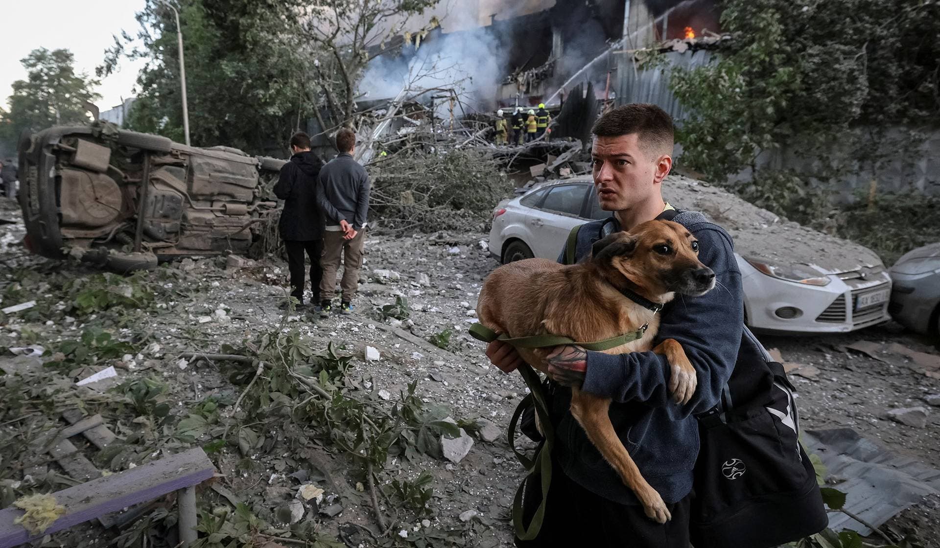 A resident with a dog walks at a site of a Russian drone and missile strike in Kyiv