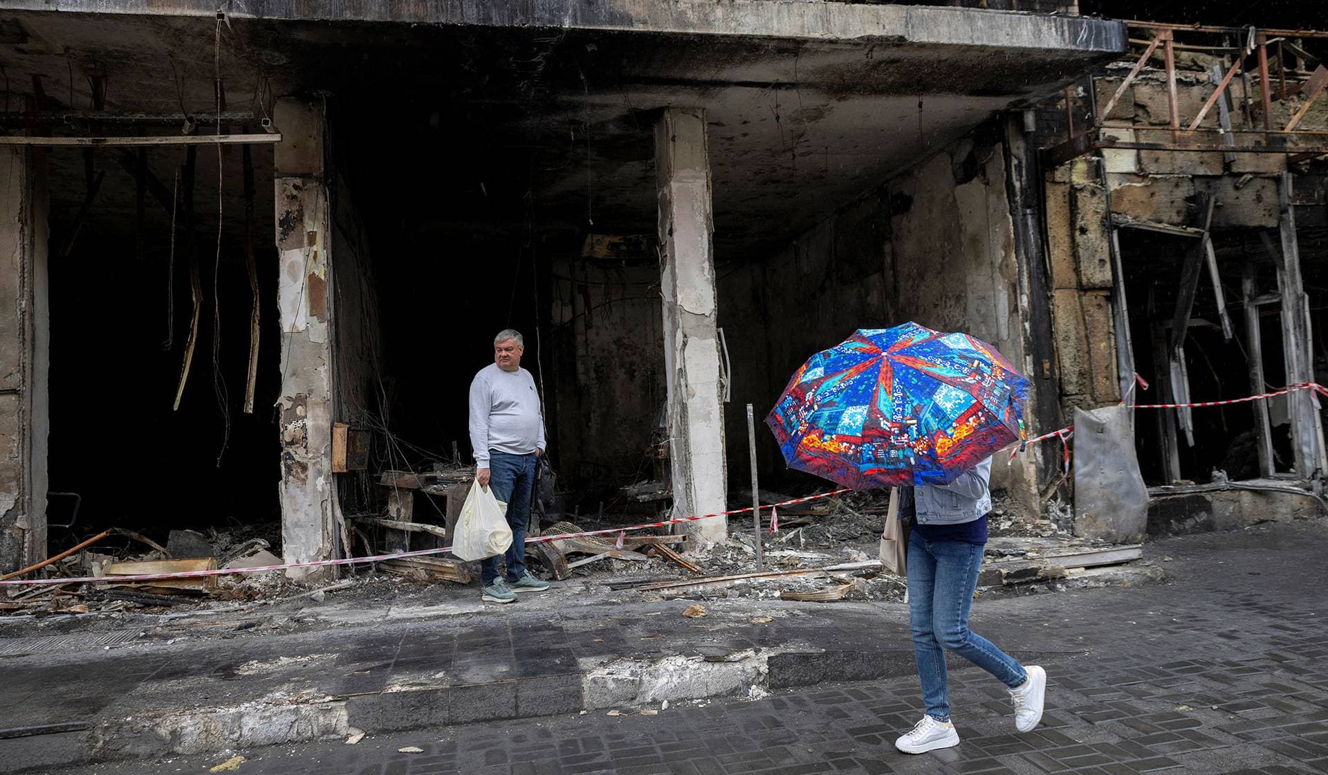 A man stands in front of a destroyed shop in a neighborhood that was badly damaged during Sunday's Russian missile and drone attack in Kyiv