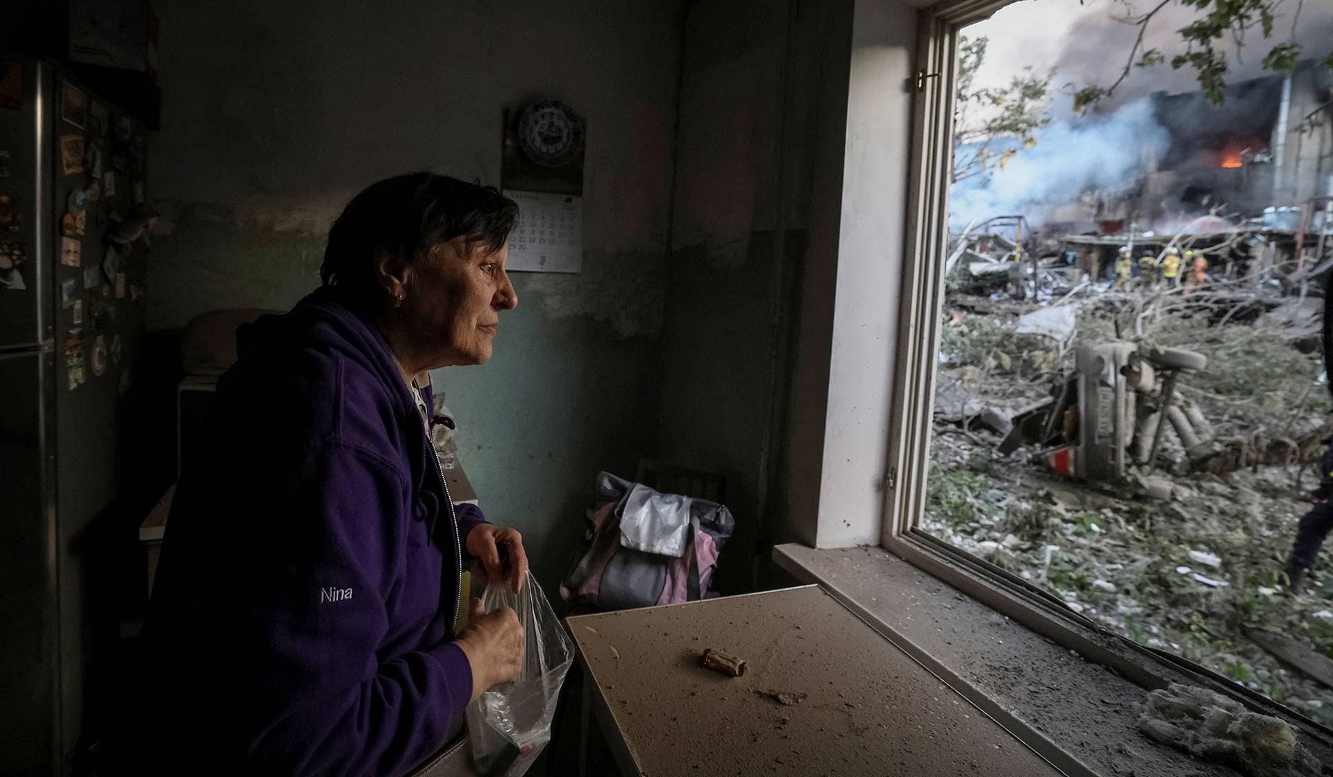 A resident looks from a broken window at a site of a Russian drone and missile strike in Kyiv