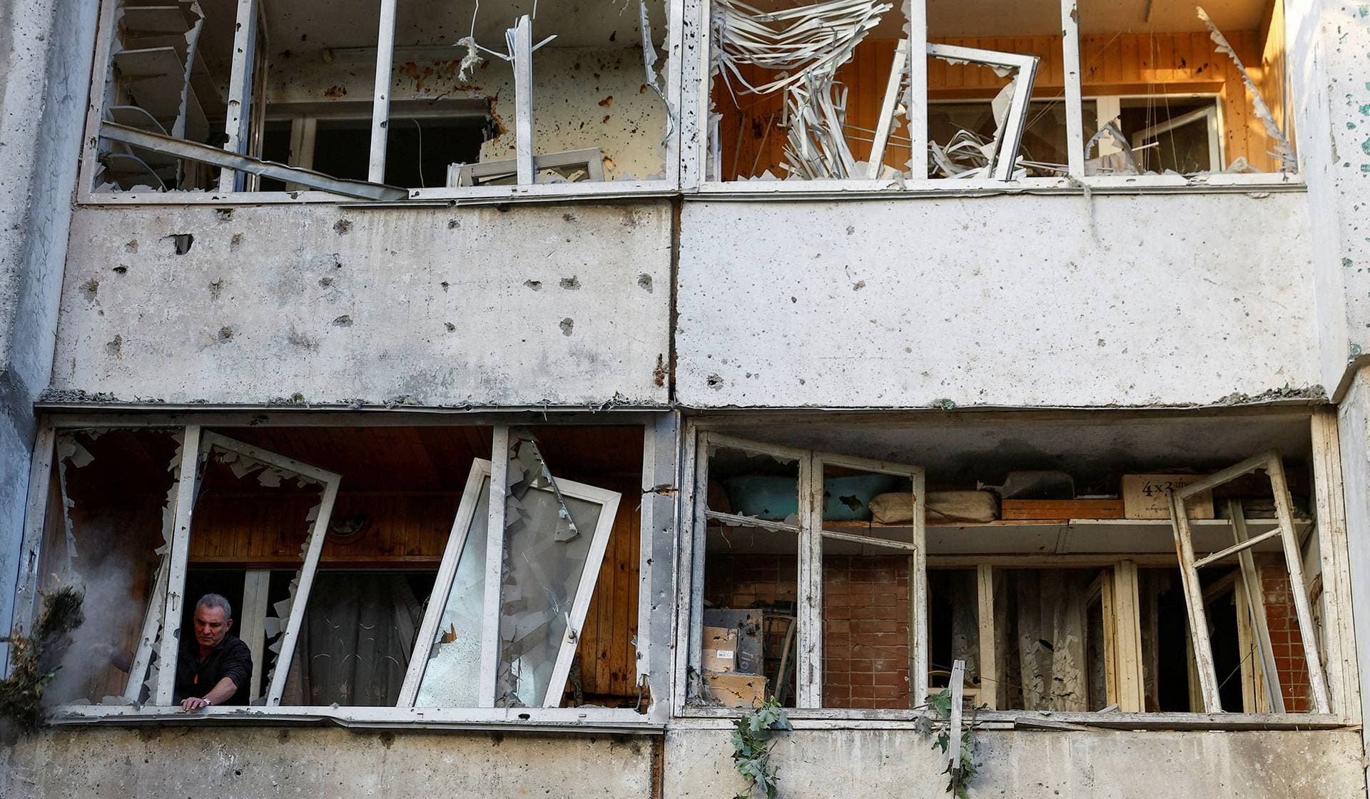 A man inspects a building damaged during Russian missile and drone strikes in Kyiv