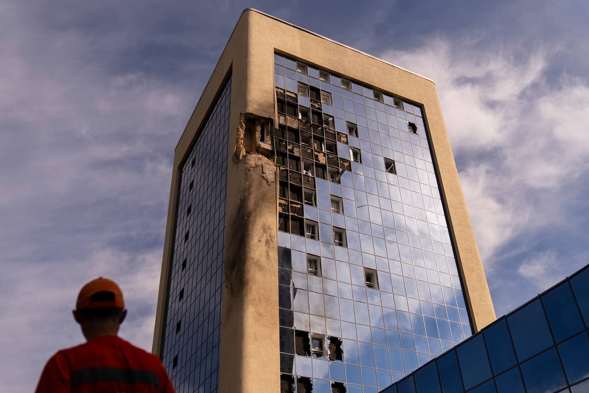 A maintenance worker stands outside a damaged government building in Kyiv