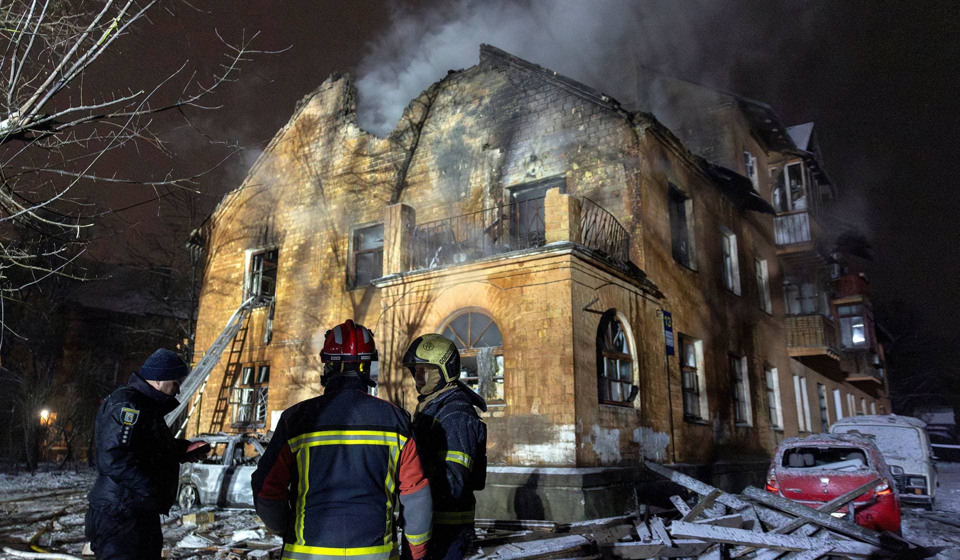 Firefighters stand in front of a residential building that was hit during a night of Russian drone and missile attacksin Kyiv