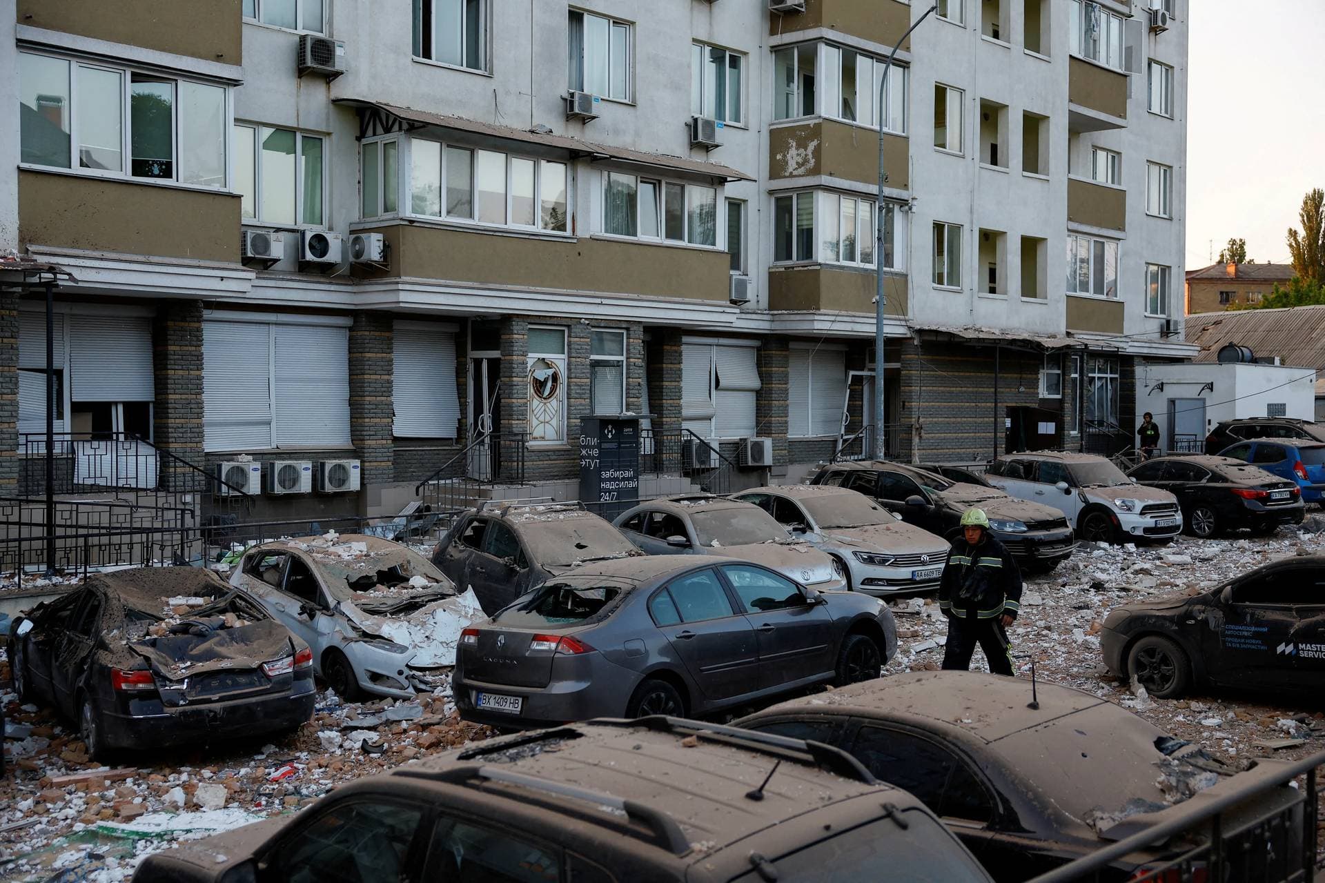 A firefighter walks between cars damaged during the latest Russian drone strike on Kyiv