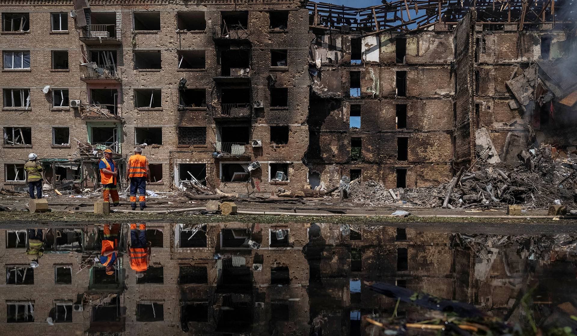 Communal workers clean an area at the site of a Russian missile and drone strike in Kyiv