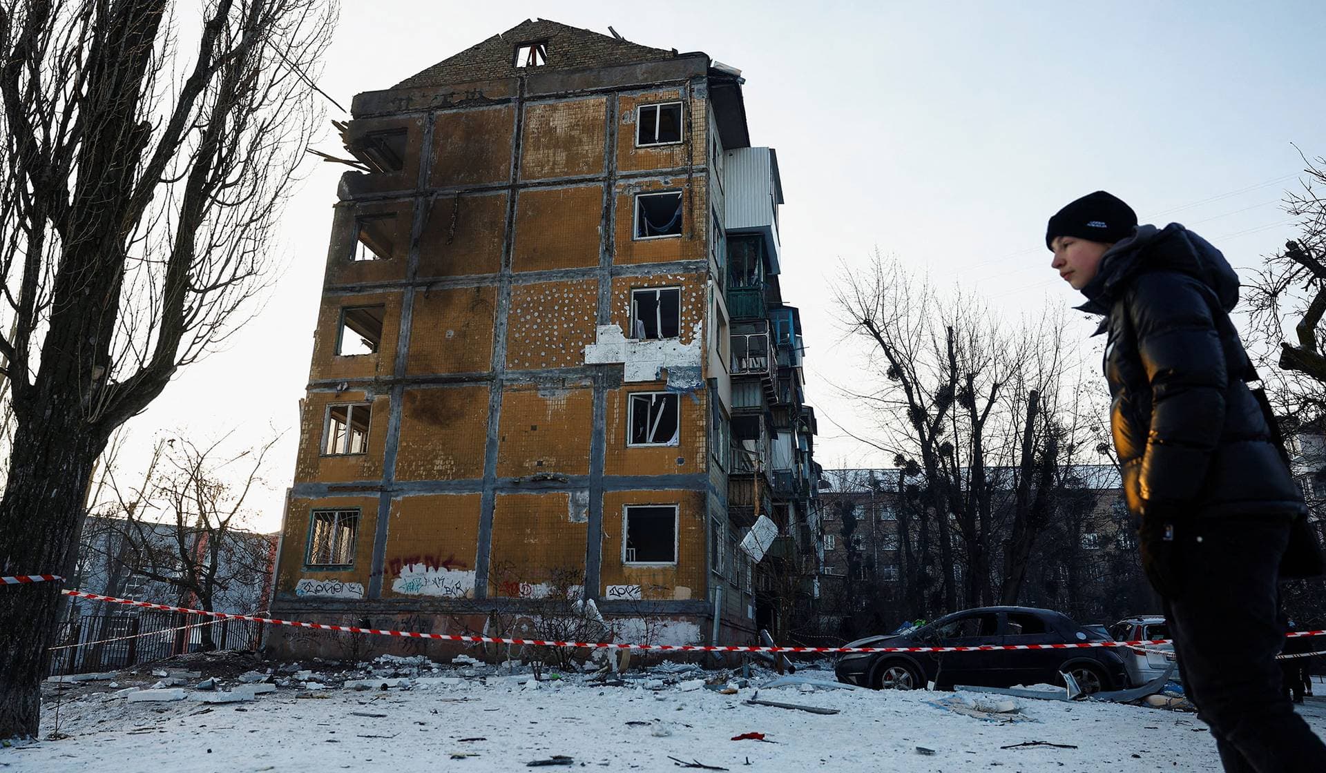 A resident stands next to an apartment building hit by a Russian drone strike in Kyiv