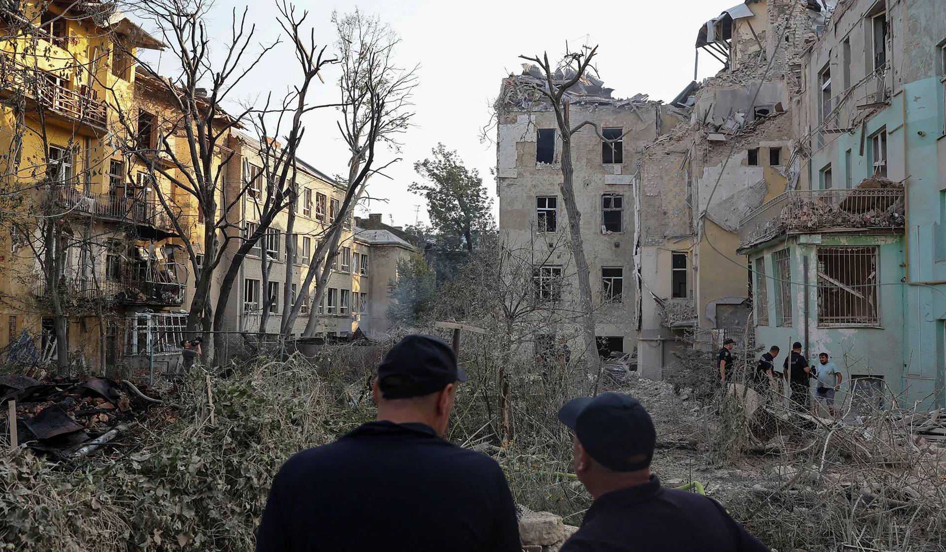 Emergency workers stand next to residential buildings damaged during a Russian drone and missile strike in Lviv