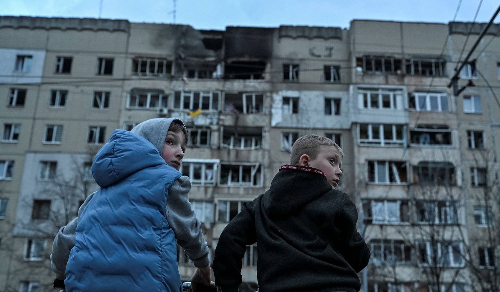 Boys on bicycles stand at the site of an apartment building hit by a Russian drone strike in central Lviv