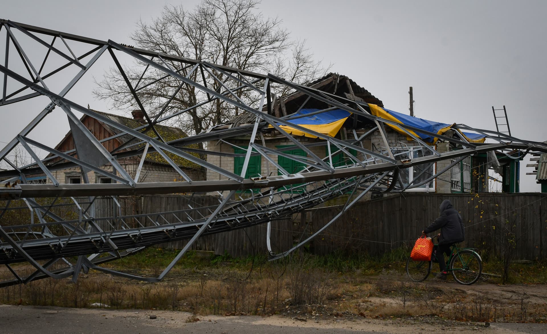 A woman rides a bicycle past destroyed buildings in the recently recaptured village of Yampil
