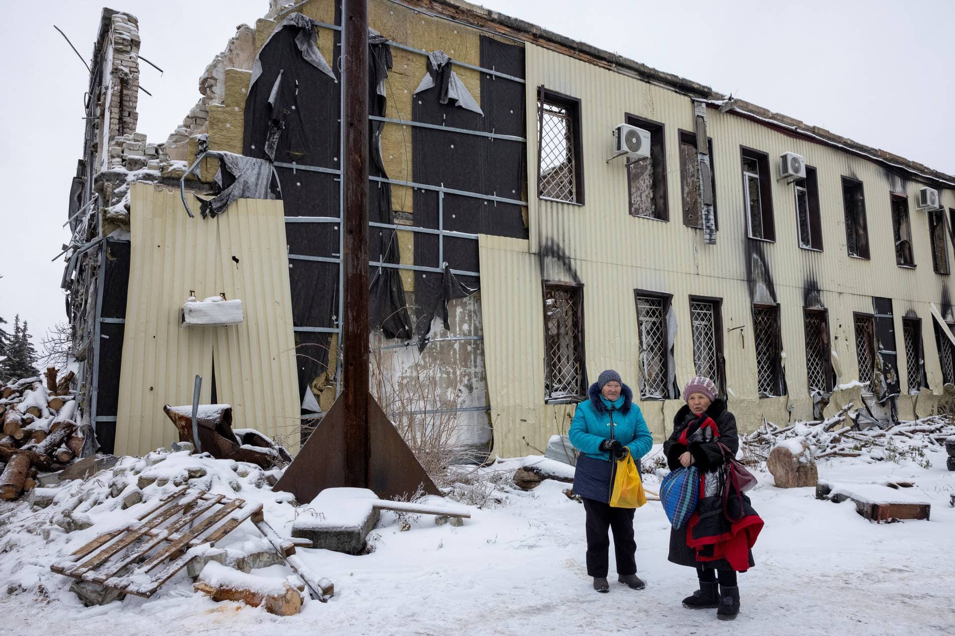 Local residents wait to pick up wood to heat their homes outside a court that was destroyed by an air strike in the front-line town of Lyman