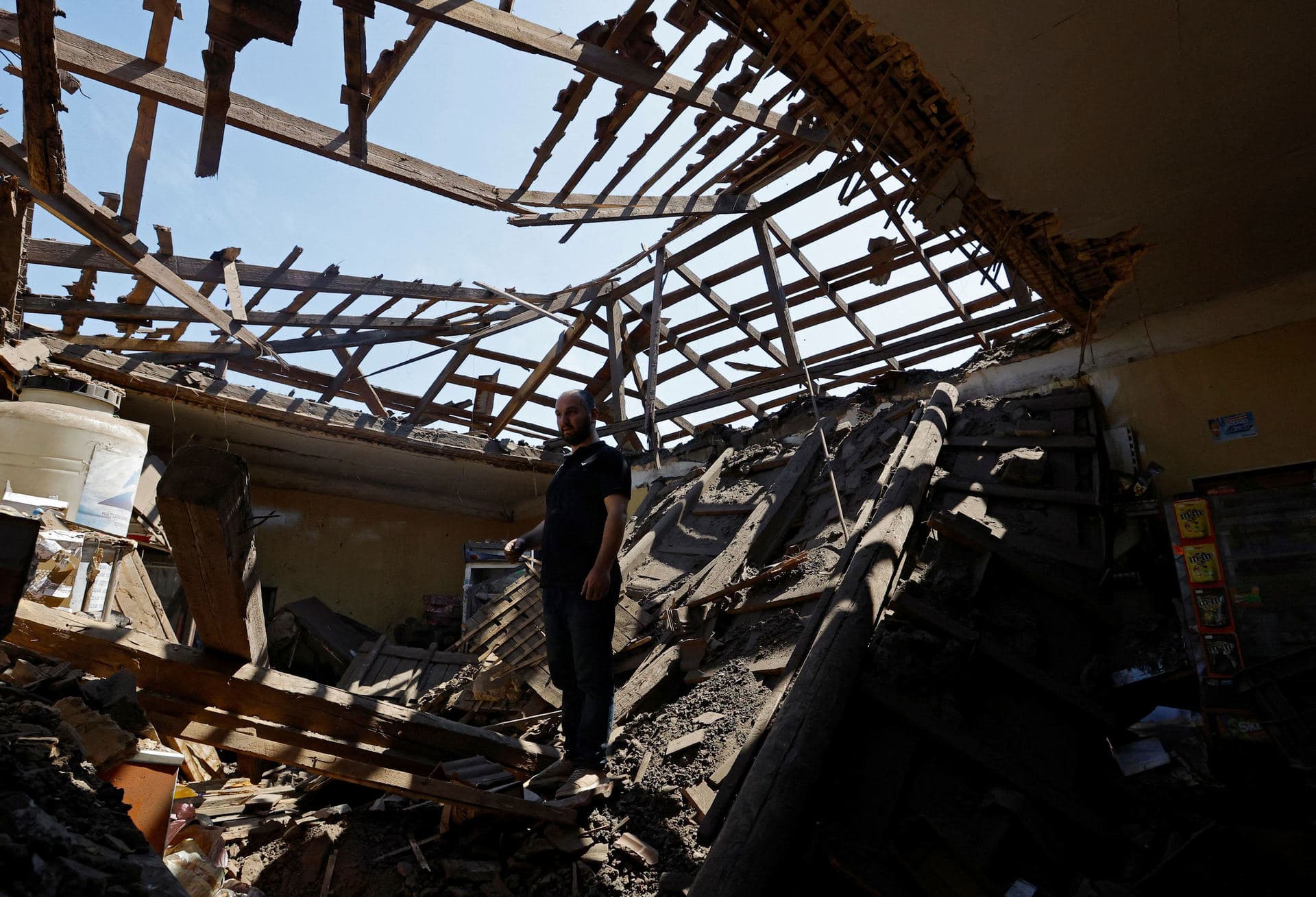 Local resident stands inside the shop he rents, which was destroyed by recent shelling in Makiyivka