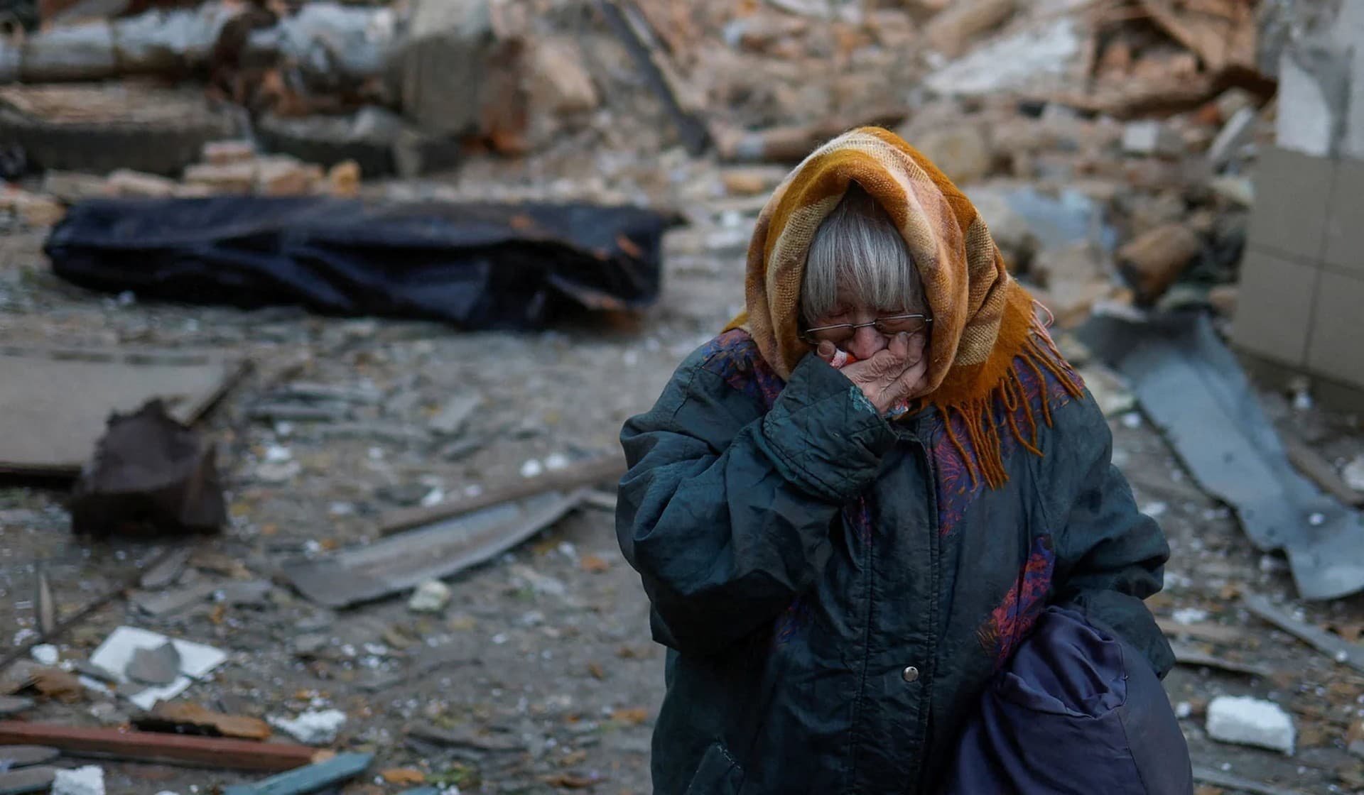 A woman reacts next to the body of her neighbor found under debris of a residential house destroyed by a Russian missile attack in Mykolaiv