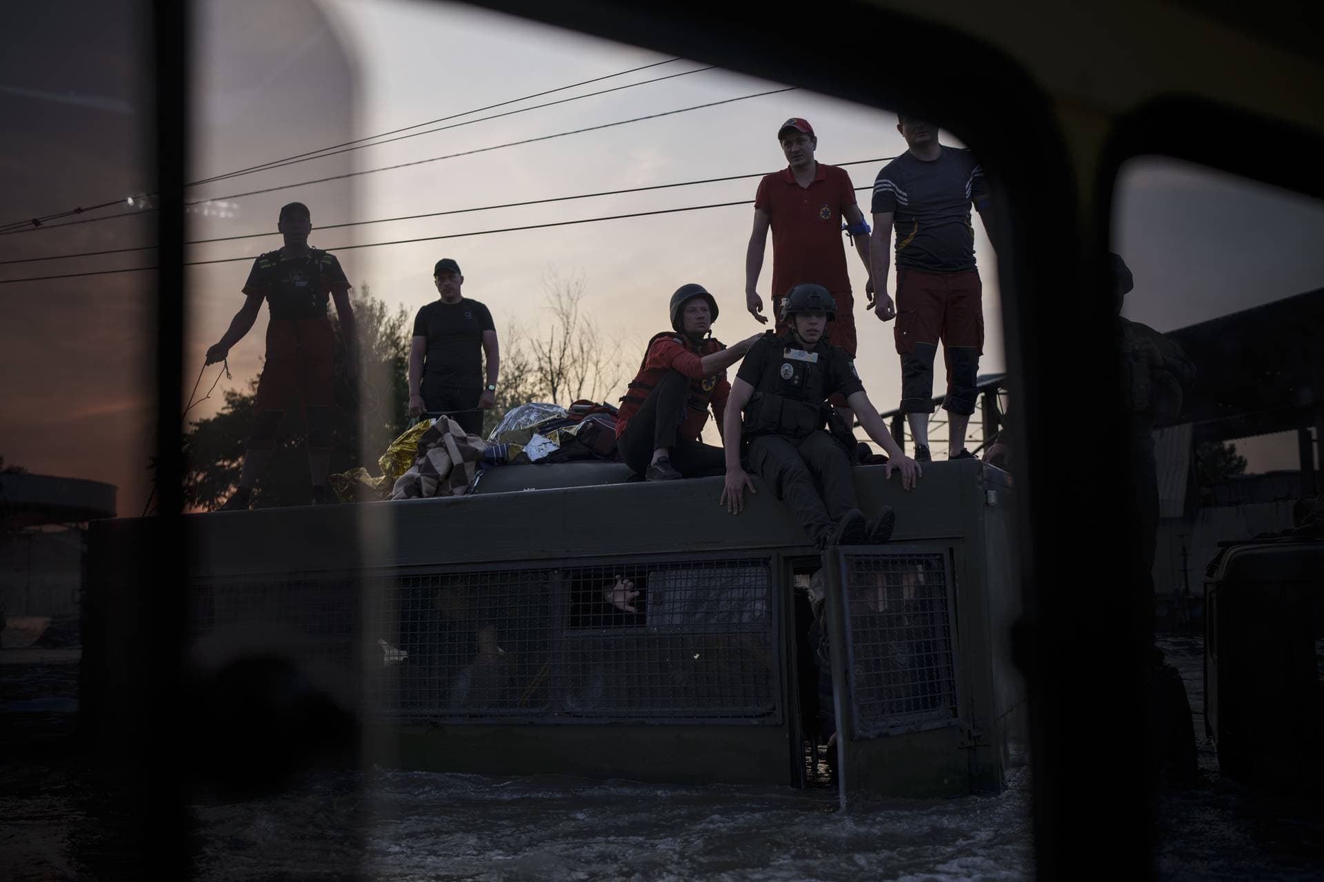 People are seen in and on top of an army truck as emergency responders work during evacuations following the Nova Kakhovka dam breach