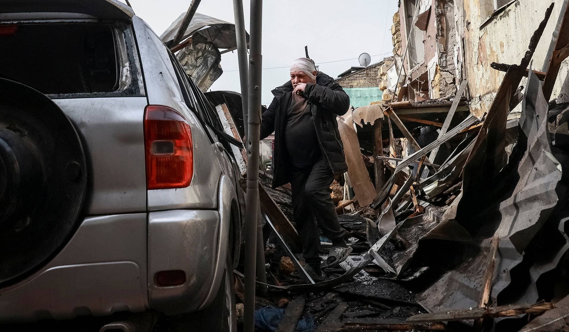 A wounded resident observes his damaged car near an apartment building hit by a Russian drone strike in Odesa